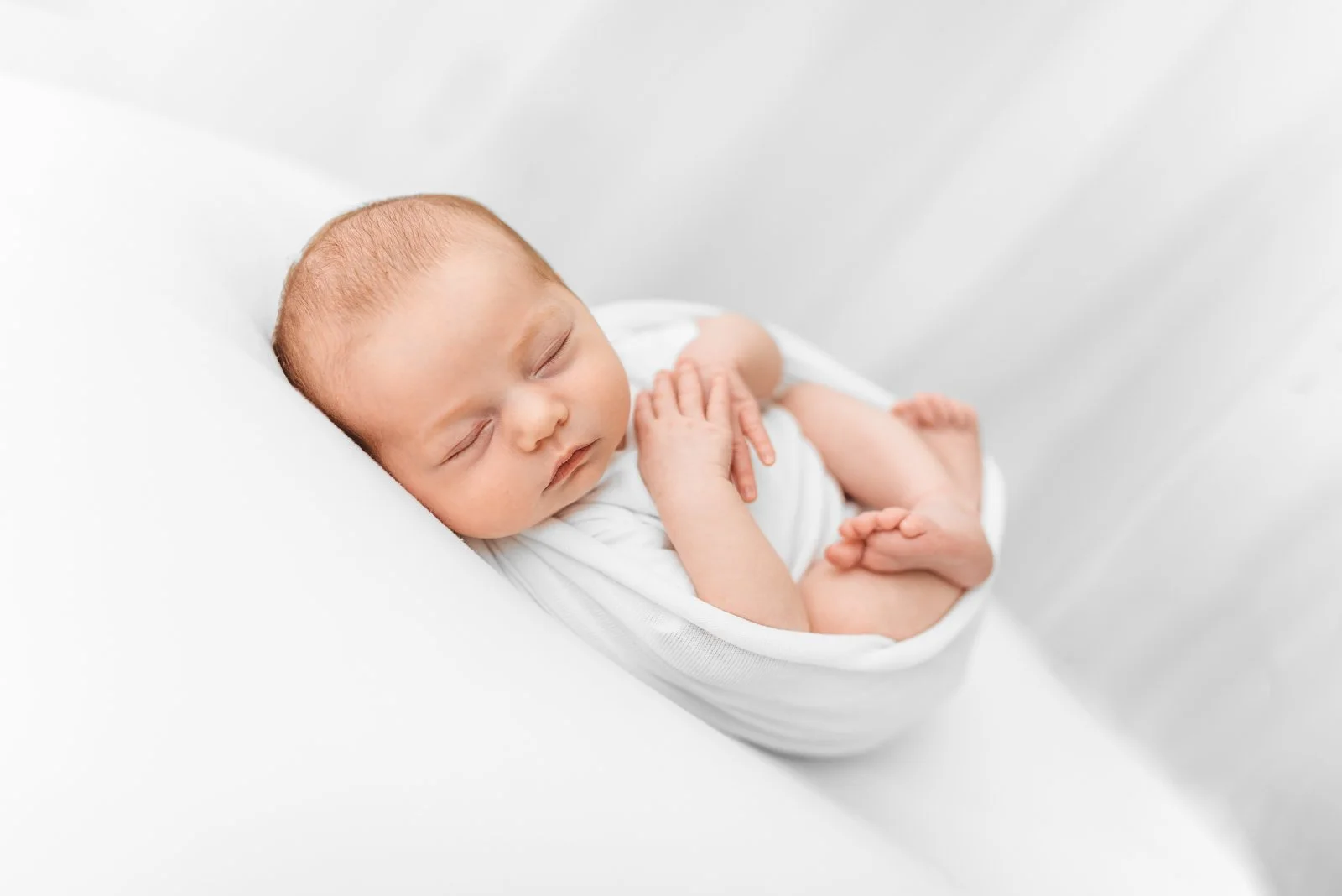 Newborn baby girl wrapped in neutral tones during a Wokingham photography session