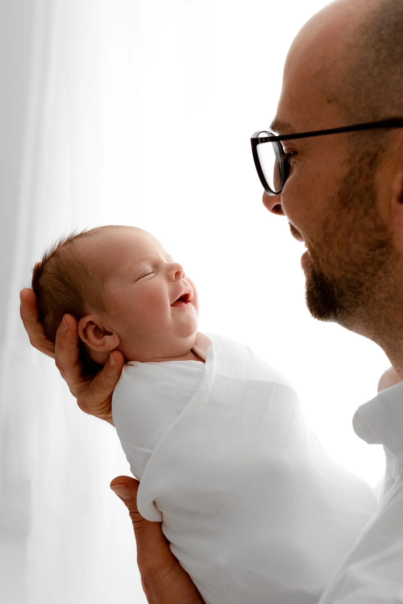 Parent holding their newborn baby during a calm photoshoot session