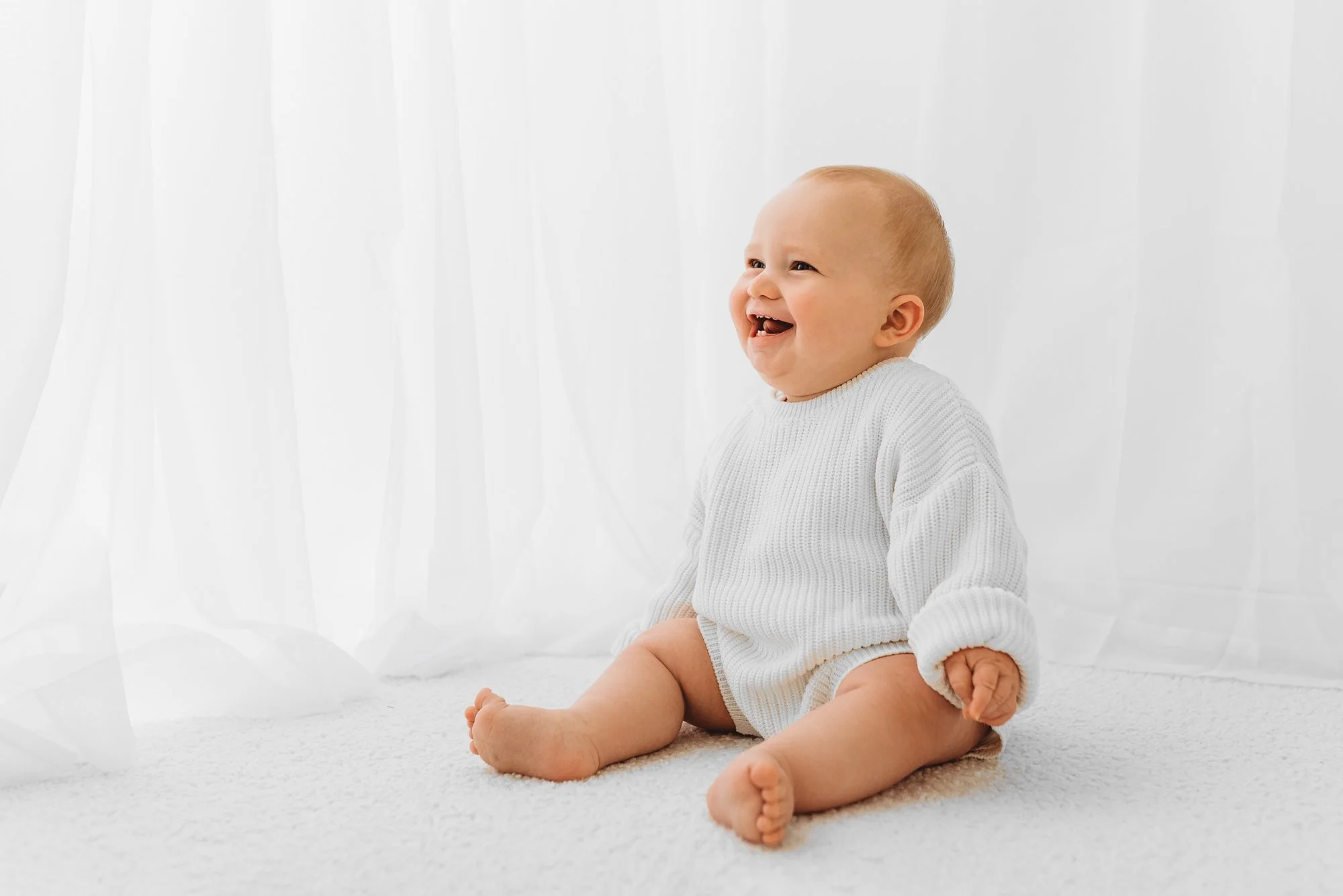 Baby sitting confidently during a milestone photography session