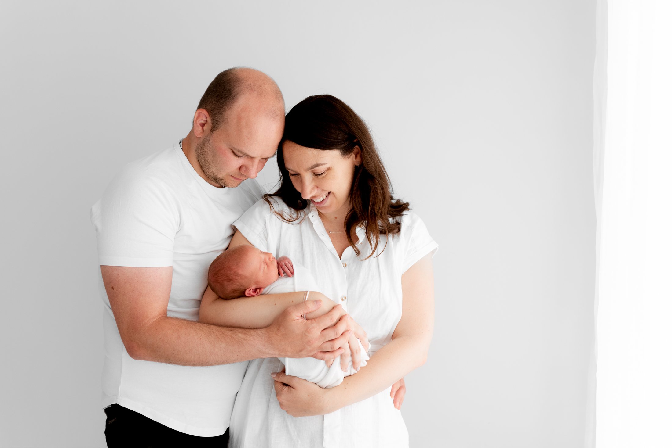 Parents holding their newborn baby during a relaxed photoshoot session