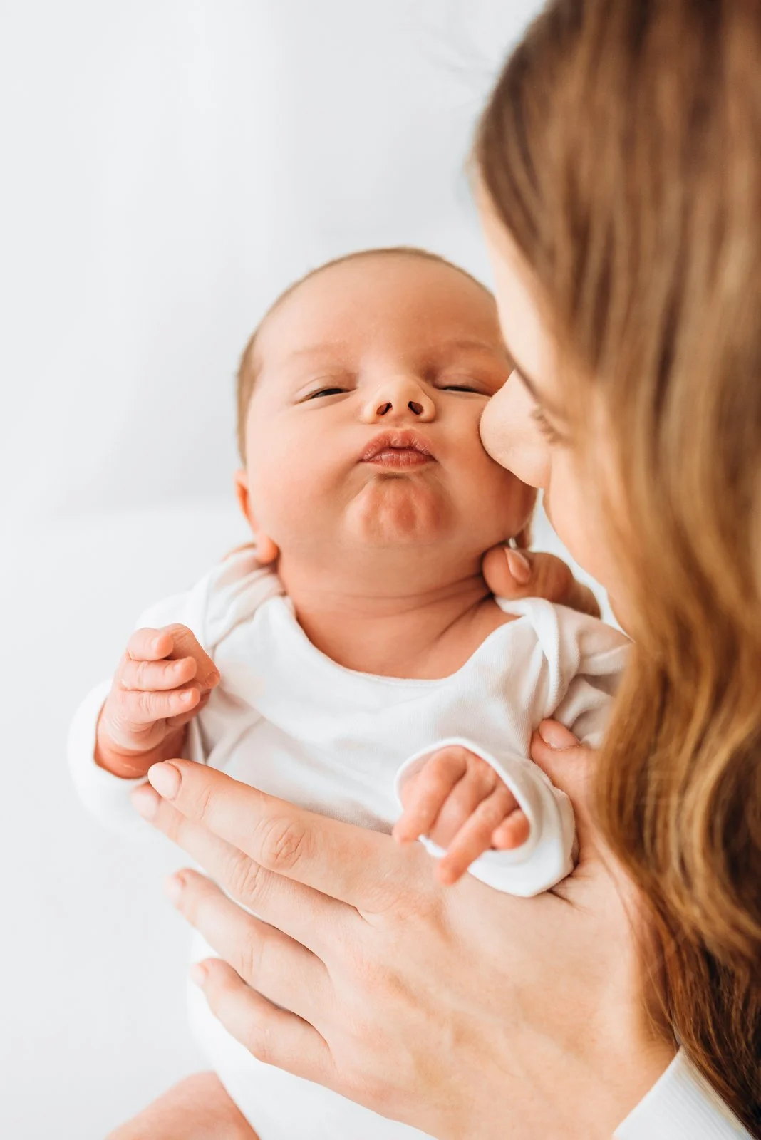 Mother cuddling her newborn baby in soft natural light during a relaxed newborn session in Berkshire