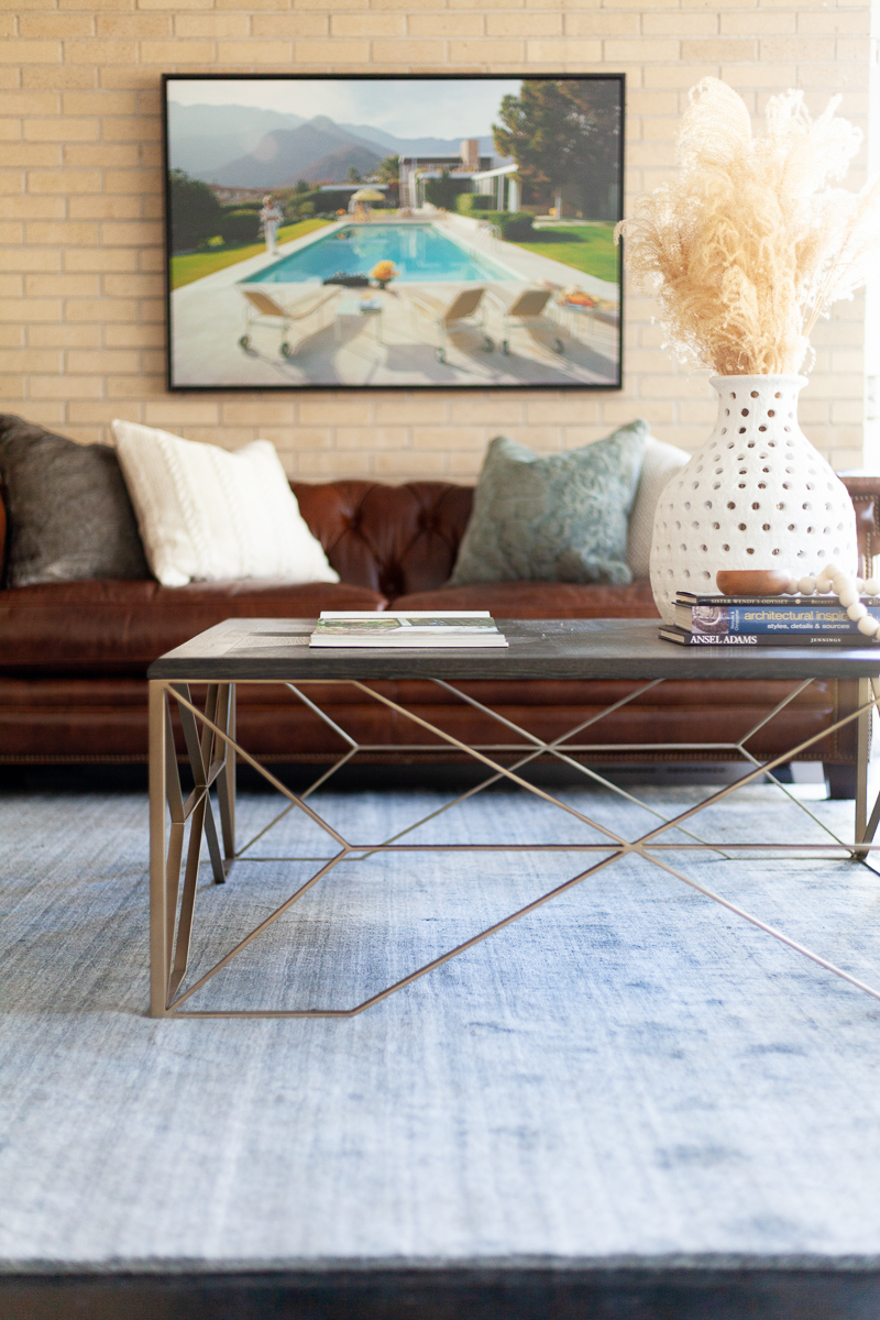 At the rooms center, clean lines & geometric shapes from the Theodore Coffee Table balance the natural textures from the porous vase and bone styling beads . The mixing of these modern and natural elements bring bring a sophisticated eclecticism into the space.