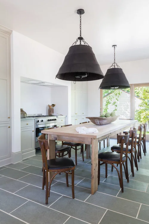 Large, industrial island pendants are featured above a table for ten. (Photography by Alyssa Rosenheck )