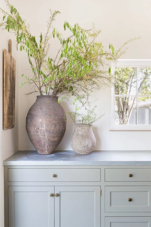 A corner of the kitchen is simply styled using weathered pottery and a rectangular cutting board. (Photography by Alyssa Rosenheck )