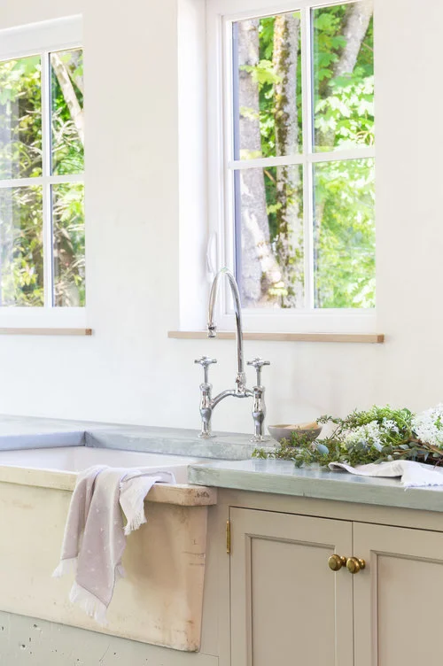 The large farmhouse sink with nickel faucet fixture is placed below the windows, providing a stunning view of the outdoors. (Photography by Alyssa Rosenheck )