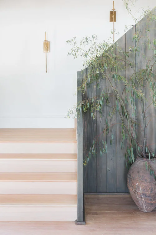 Thin candle sconces, antique ceramic vase, & vertical fence-like railing create a chic, yet rustic entry area. (Photography by Alyssa Rosenheck )