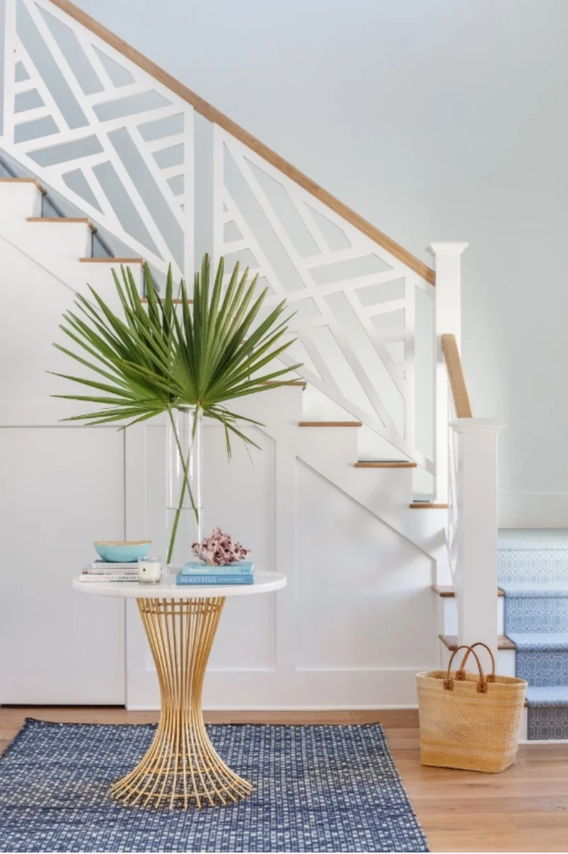 The entryway features an hourglass accent table on a woven blue rug.