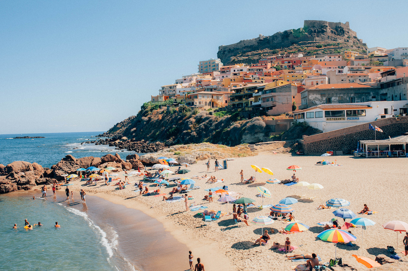 No. 104 ”Colorful Castelsardo” Art starting at $73.40 | Photographed in Castelsardo, Sardinia, this lively beach is surrounded by orange-toned modern architecture in perfect contrast with Castello dei Doria. The castle was built around the 12th century and is a reminder of the rich history of Italy.