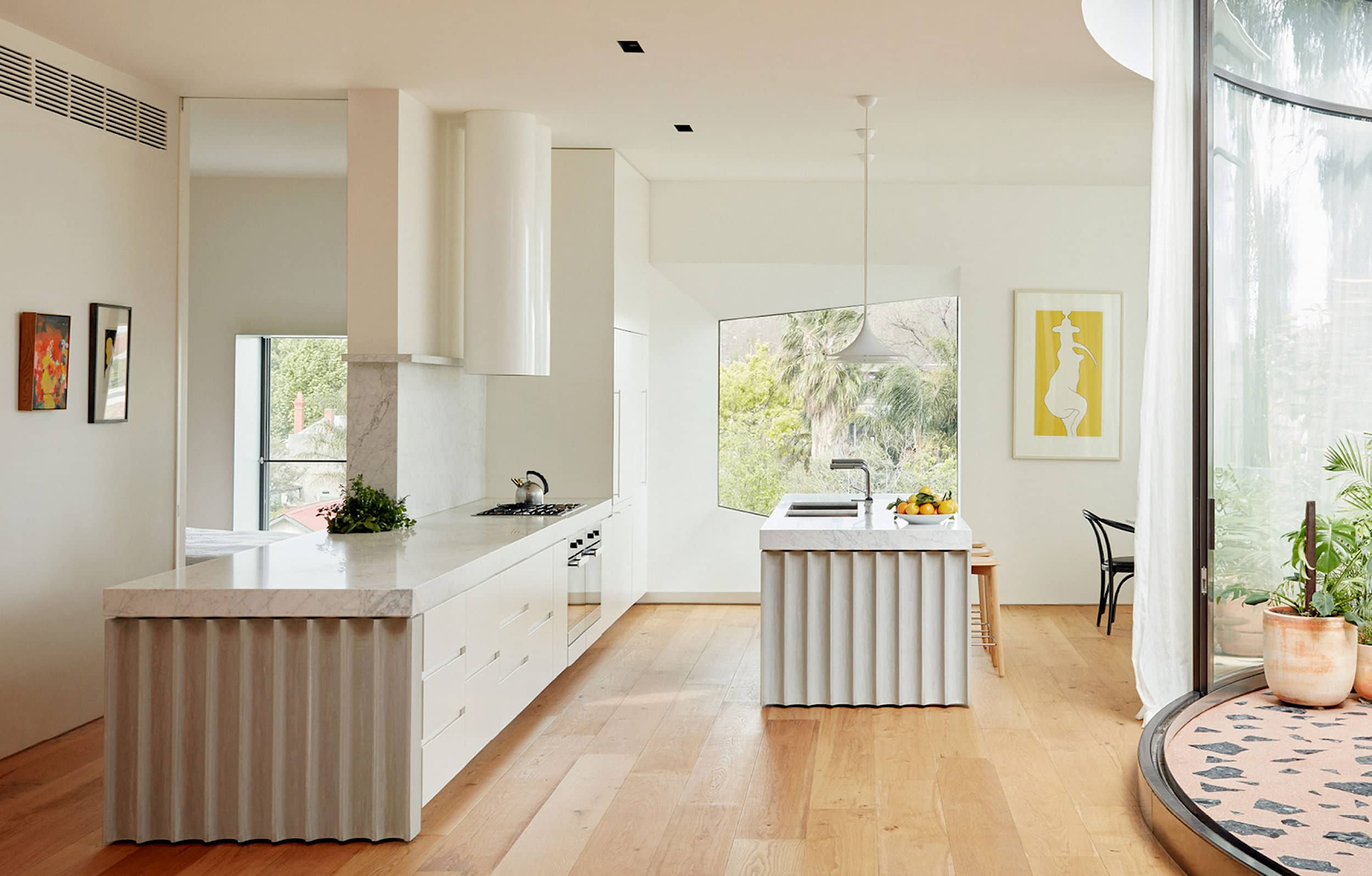 Design by Anon Studio | Photography by Tom Ross & Freadman White A fluted touch to the cabinetry and kitchen island are right at home amongst terrazzo, white lighting, and sleek, hardware-less cabinetry.