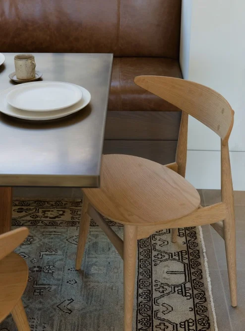 Mid-century modern meets old-schoolhouse | These wooden dining chairs are the perfect compliment to the rich, leather bench and vintage rug.