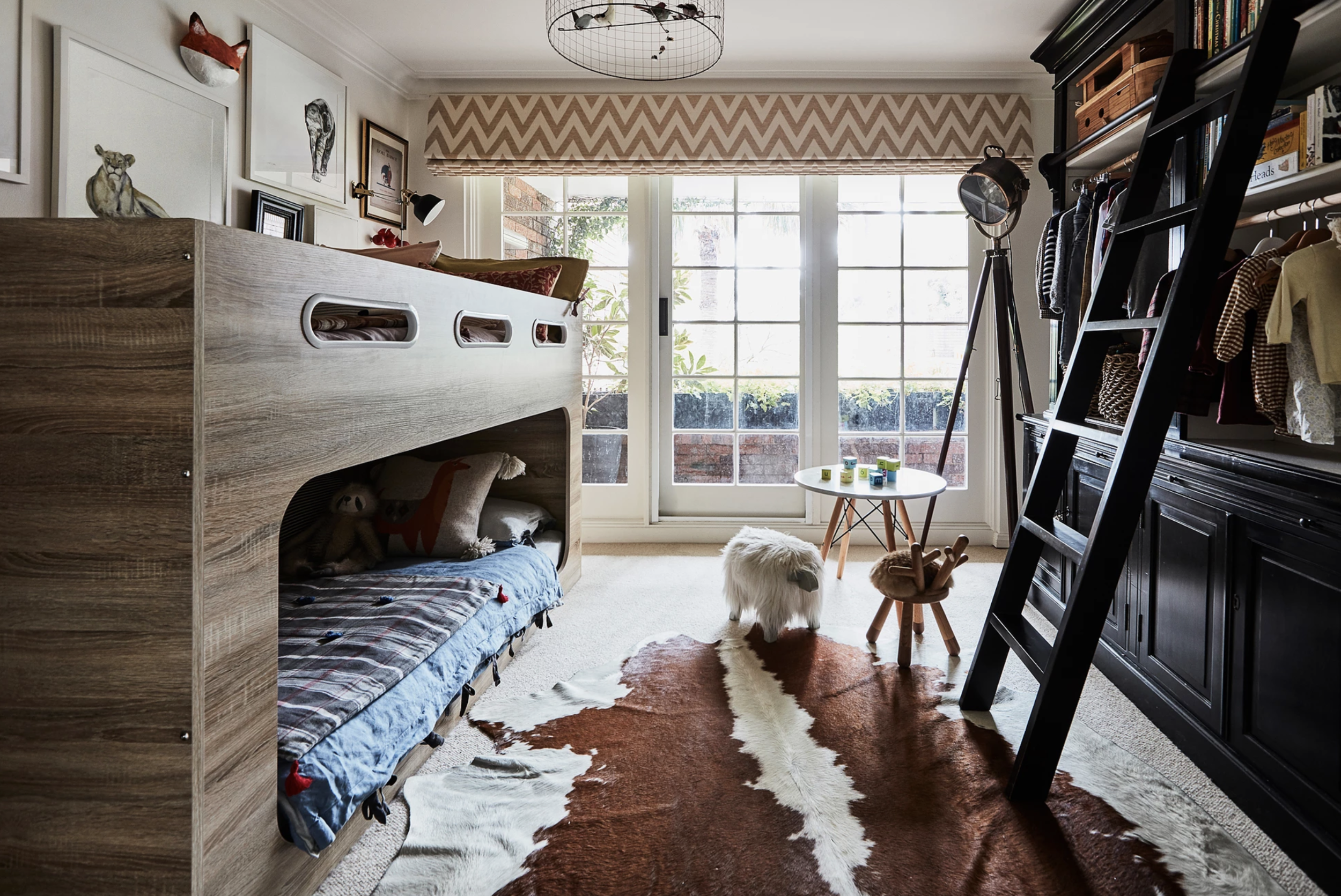 This small bedroom is jam-packed with architectural detailing and kid-friendly knick-knacks. Fun prints like the window treatment and quilts bring life to this space, and floor-length windows flood in so much natural light!