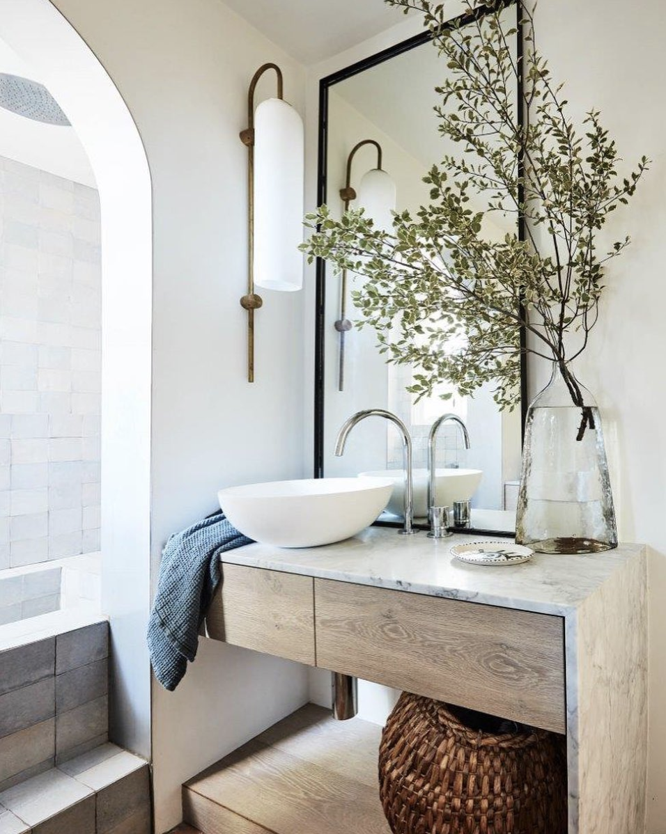 Waterfall counters, handmade Portuguese tiles, and a lengthy wall mirror create a serene atmosphere.