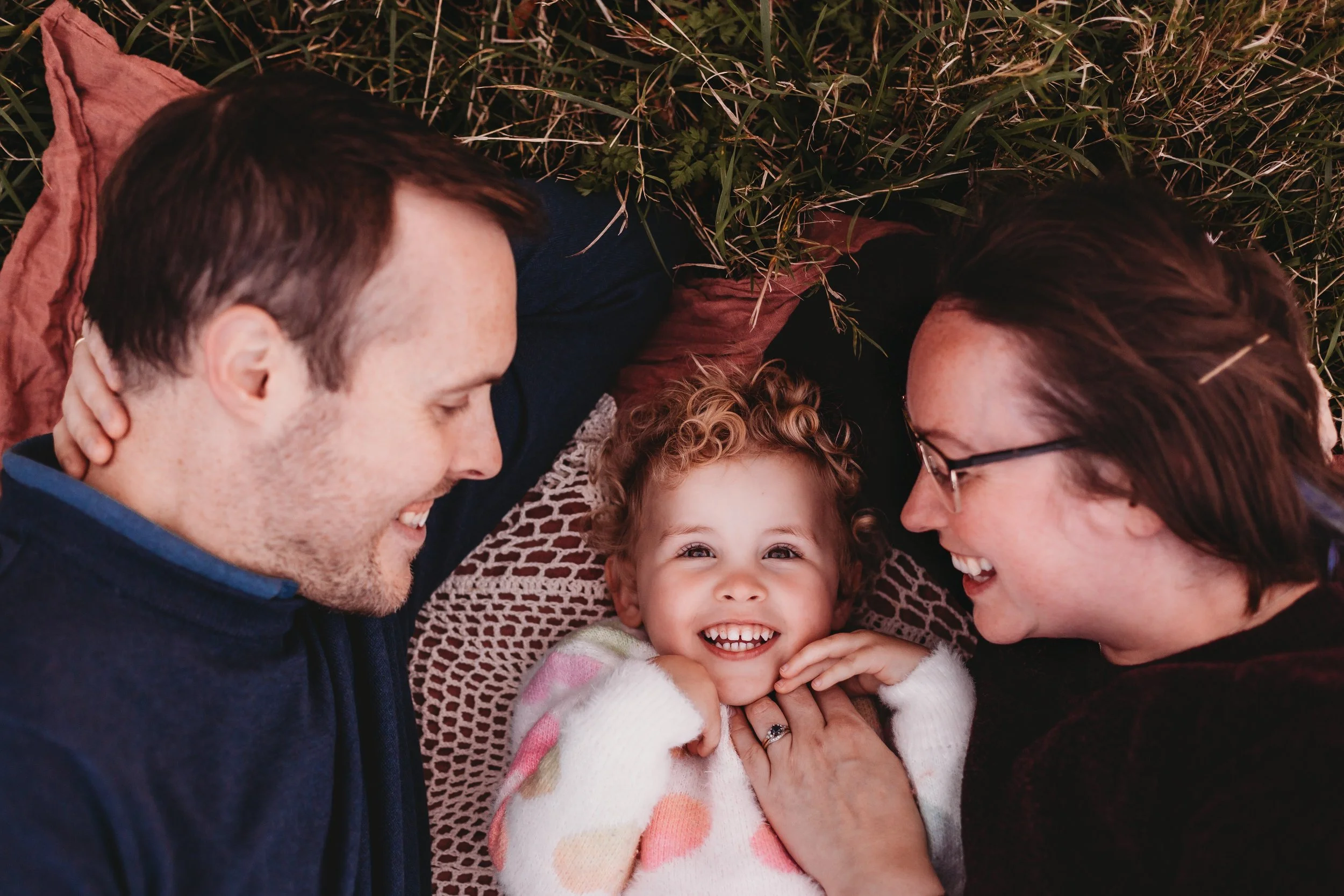 Mum, dad and daughter photo smiling on rug