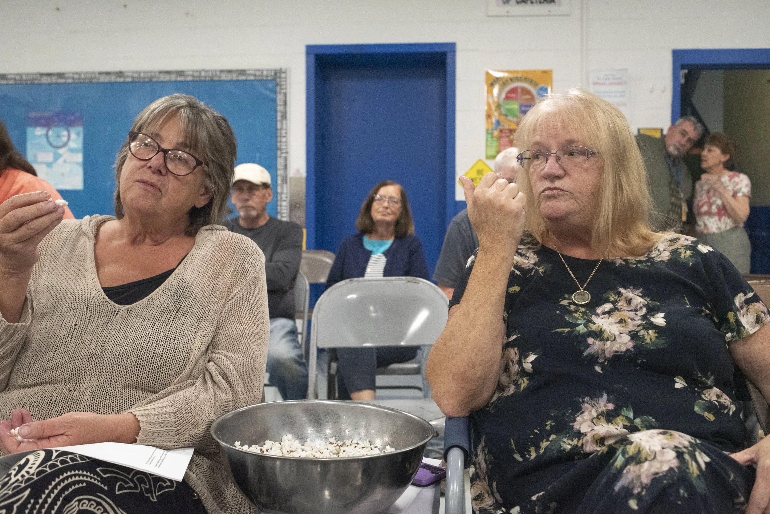  Marie Danforth, left, and Debbie Auger, eat from a bowl of popcorn during a public hearing at a city council meeting to pass a $7.3 million bond, at the high school cafeteria in Franklin, N.H., on Sept 3, 2024. The bond will fund Soldiers Memorial H