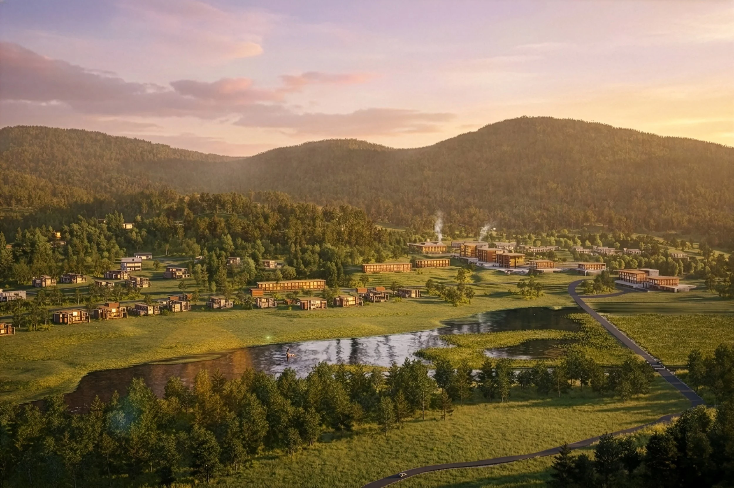 A scenic view of a hillside residential area with modern houses, a pond, and a winding road, surrounded by lush greenery and mountains in the background during sunset.