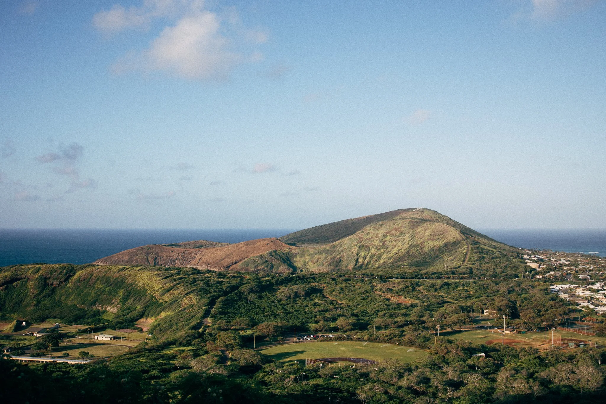 Scenic view of green hills and ocean in the distance under a clear blue sky. Located in Oahu, Hawaii