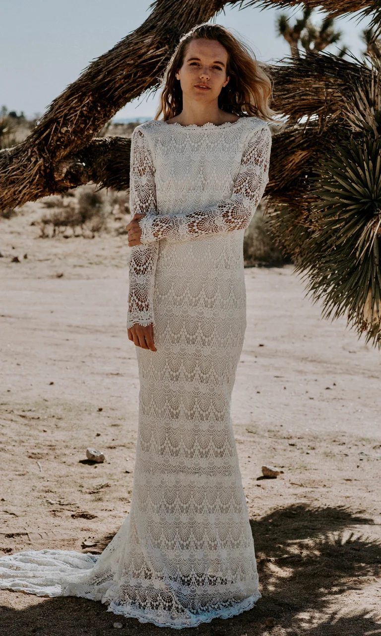 LOLA is a breathtaking bohemian luxe wedding dress made with a crochet lace for the bride who wants a vintage feel. The high neckline glides past the collarbones and is met with a deep low back perfect for any venue.