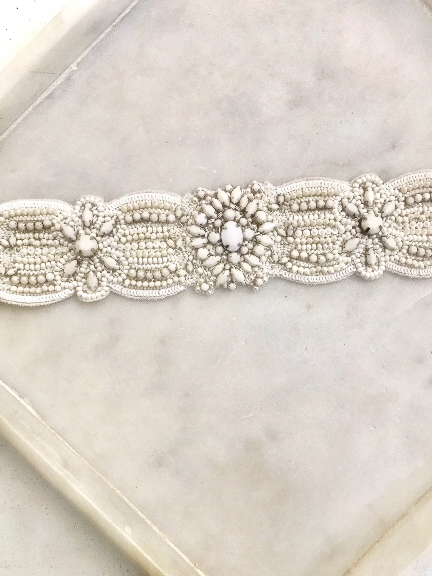 CASABLANCA BELT – This statement wedding belt features oversized crystals and off white stones that have been delicately hand woven onto silk. To be worn around the waist and ties with a silk ribbon around the back.