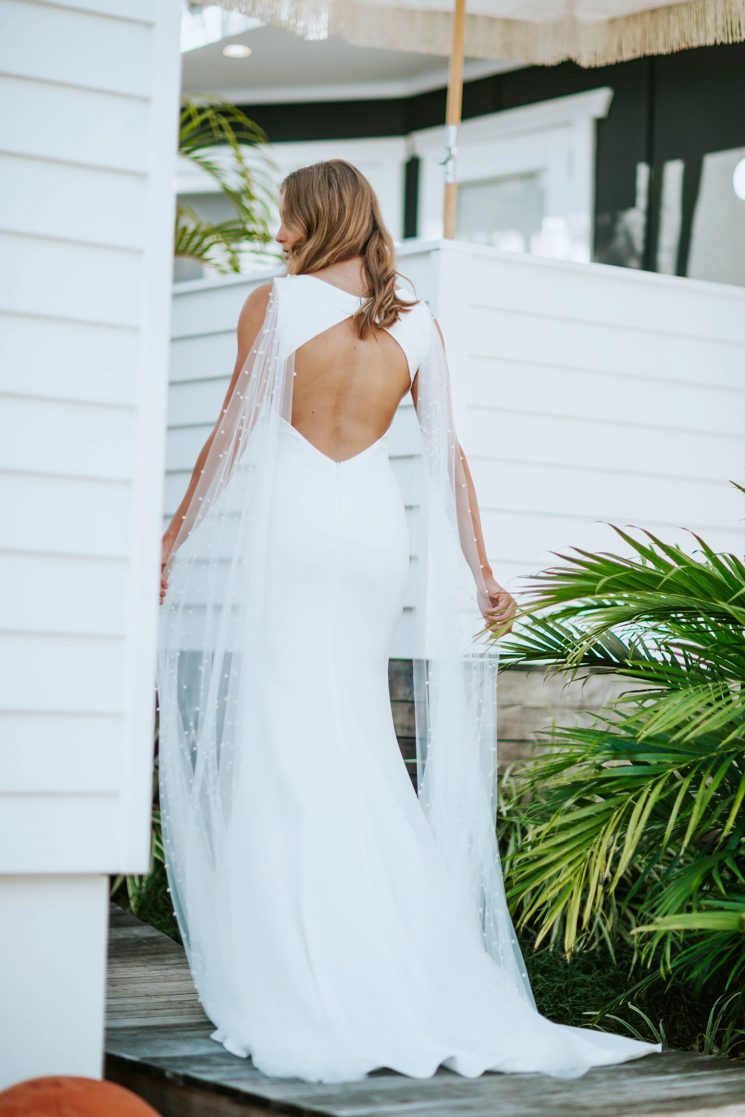 PORTUGAL was designed to cater to the versatile, modern minimalistic bride who wants it all. Her desires are ever-changing – as is this unique gown. This clean matte French crepe silhouette has multiple accessory pieces that can be added for different looks (detachable pearls, veil capes or lace trim)