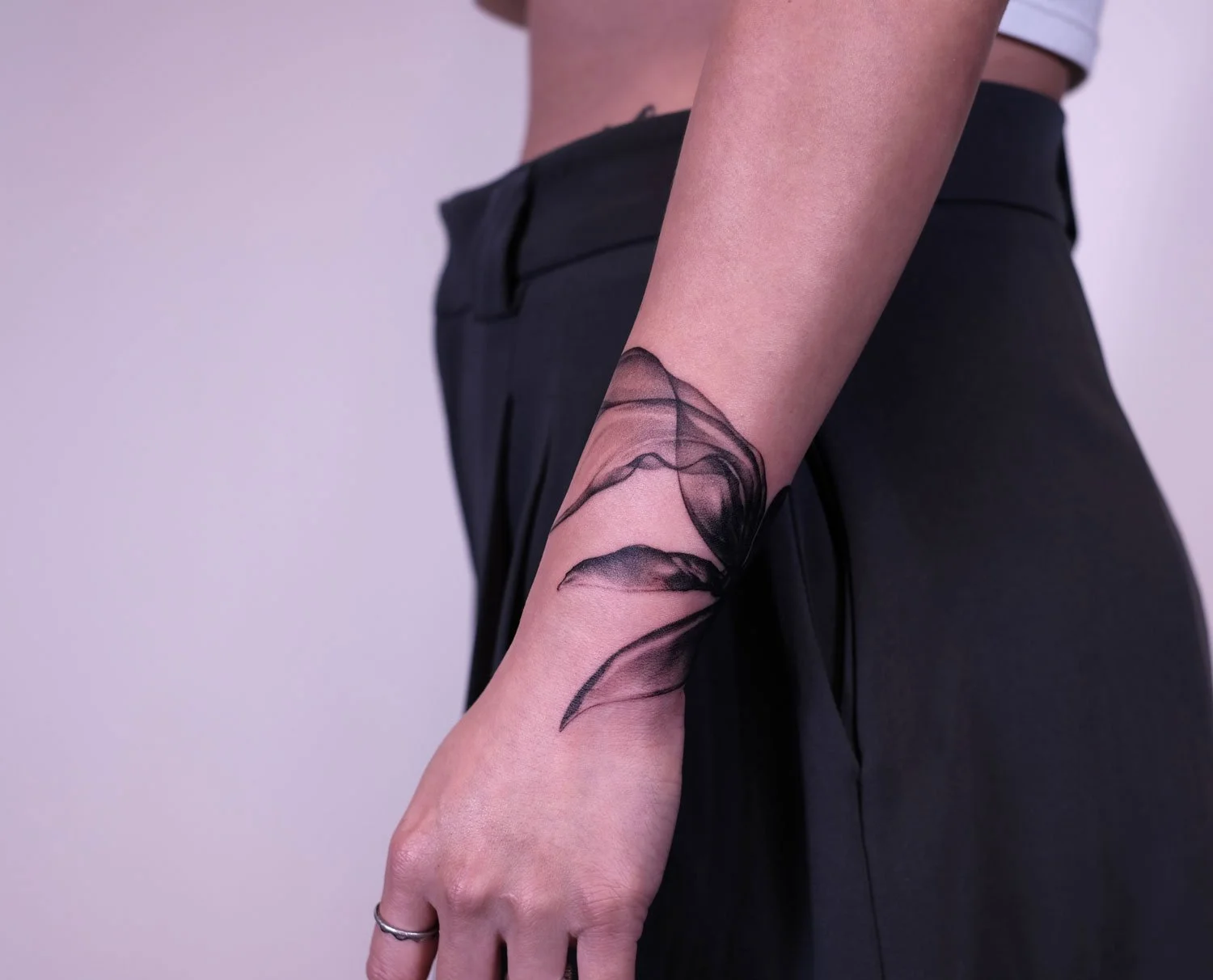 Fineline tattoo of a smoke scarf wrapped around her wrist.