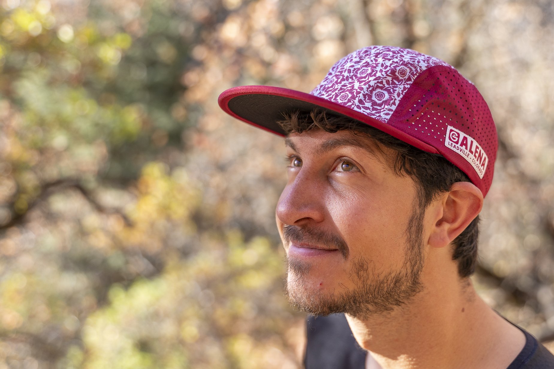 A man wearing a pink and white patterned outdoor cap with a 
