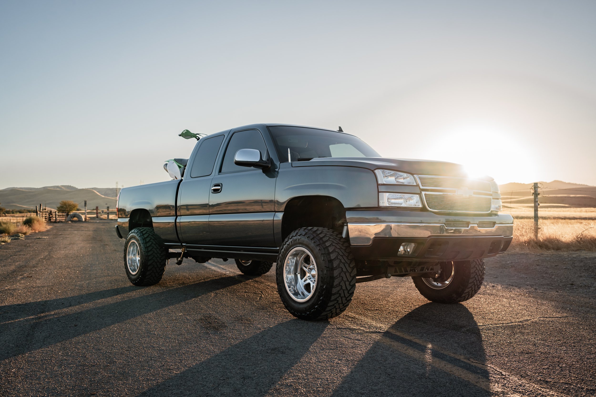 Lifted truck with dirt bike in the back at sunset on a backroad. Photo taken in Newman, CA by Mikaela Tosta Photography.