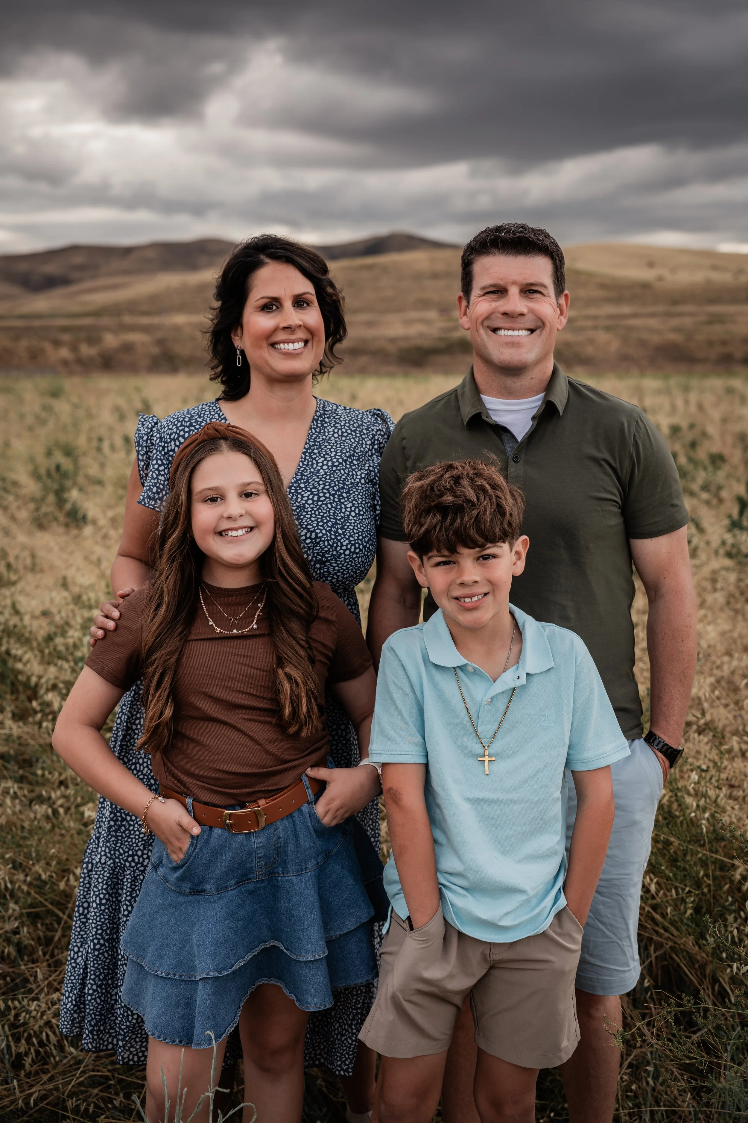 Family of four standing in an open field. Photo taken by family photographer, Mikaela Tosta Photography in Patterson, CA.