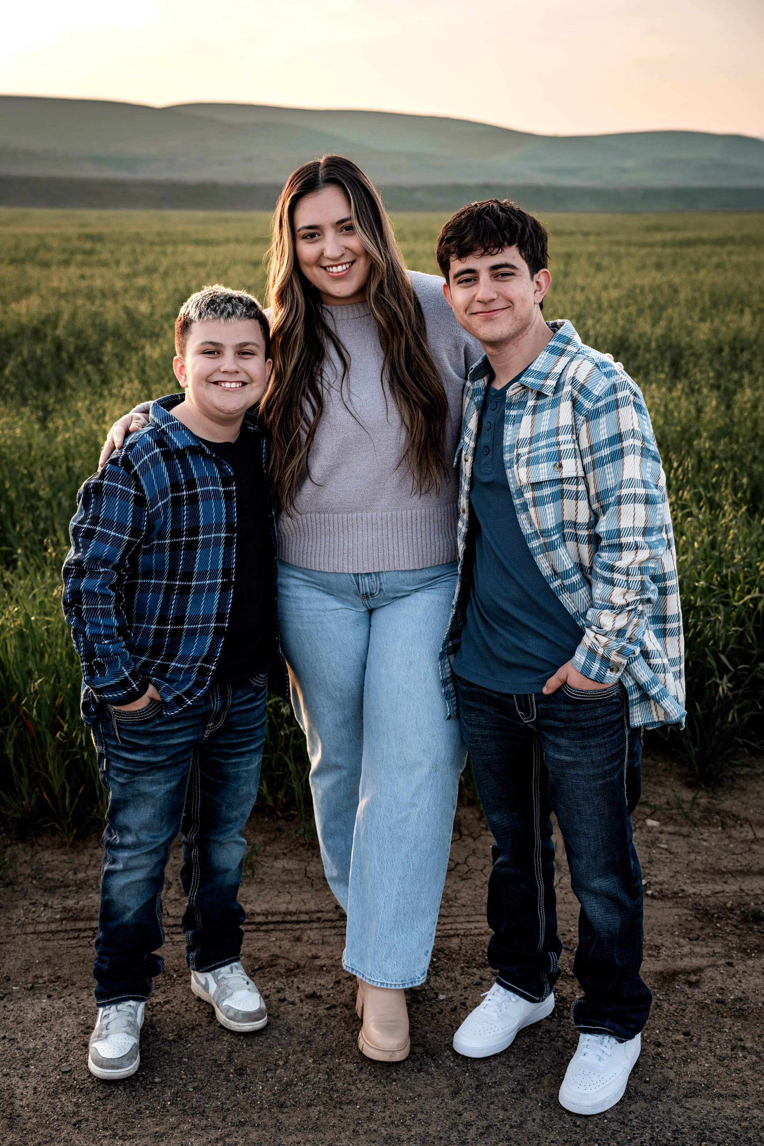 three siblings standing in an open field. Photo taken by family photographer, Mikaela Tosta Photography in Patterson, CA.