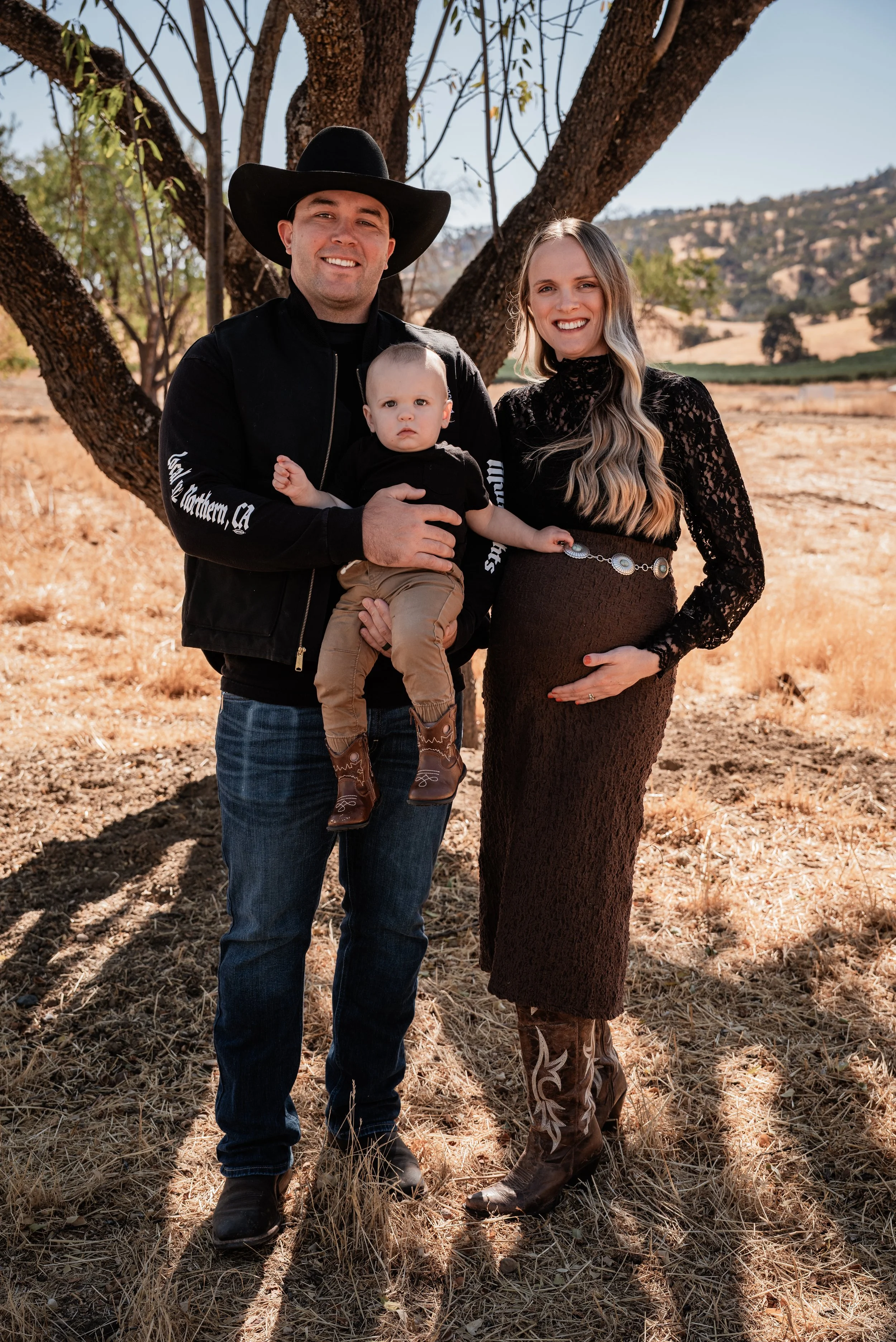 Family of three posing for a portrait in Capay, CA. Photo taken by maternity photographer, Mikaela Tosta Photography.