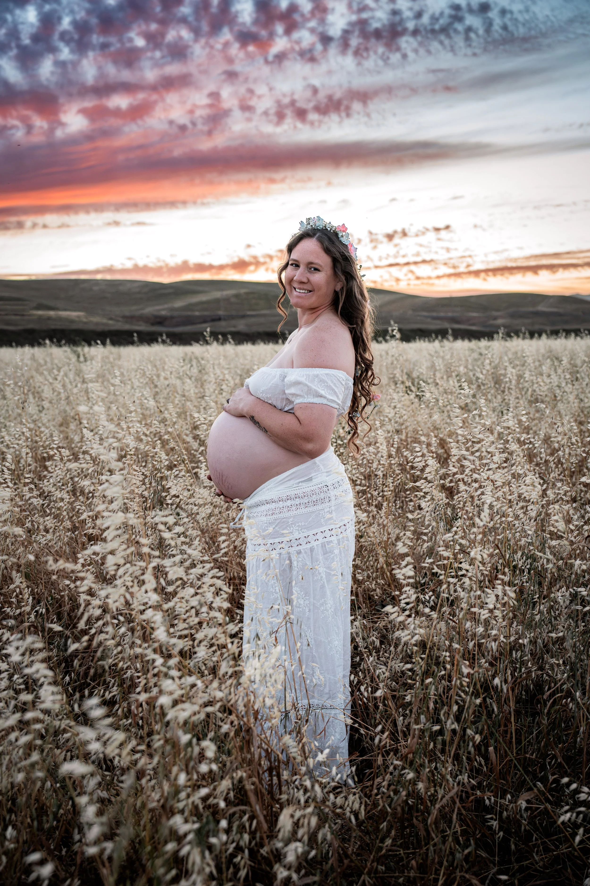 Pregnant mom holding her belly at sunset in an open field. Photo taken in Patterson, CA by Mikaela Tosta Photography.