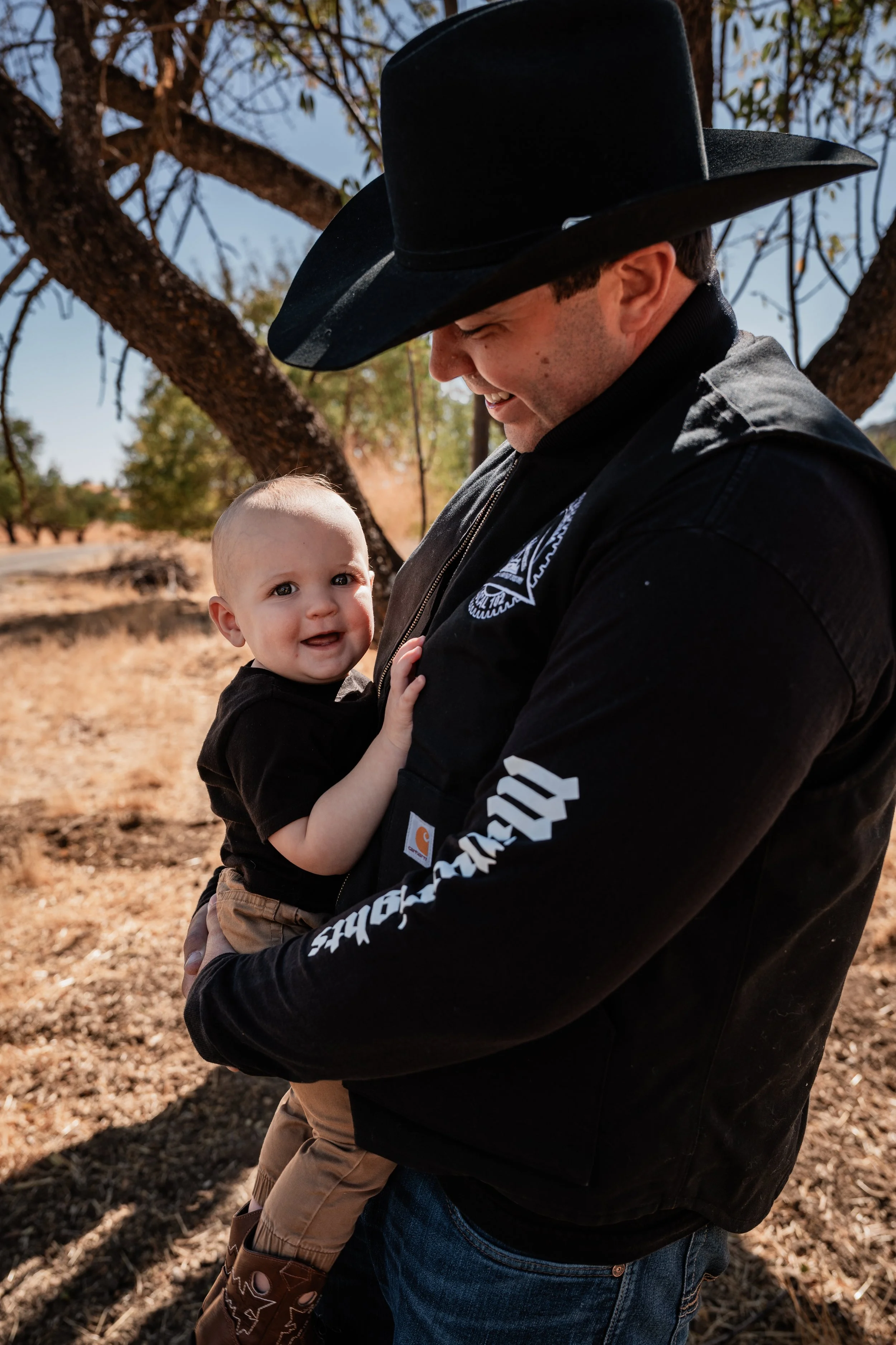 Dad holding his smiling son in Capay, CA. Photo taken by maternity photographer, Mikaela Tosta Photography.