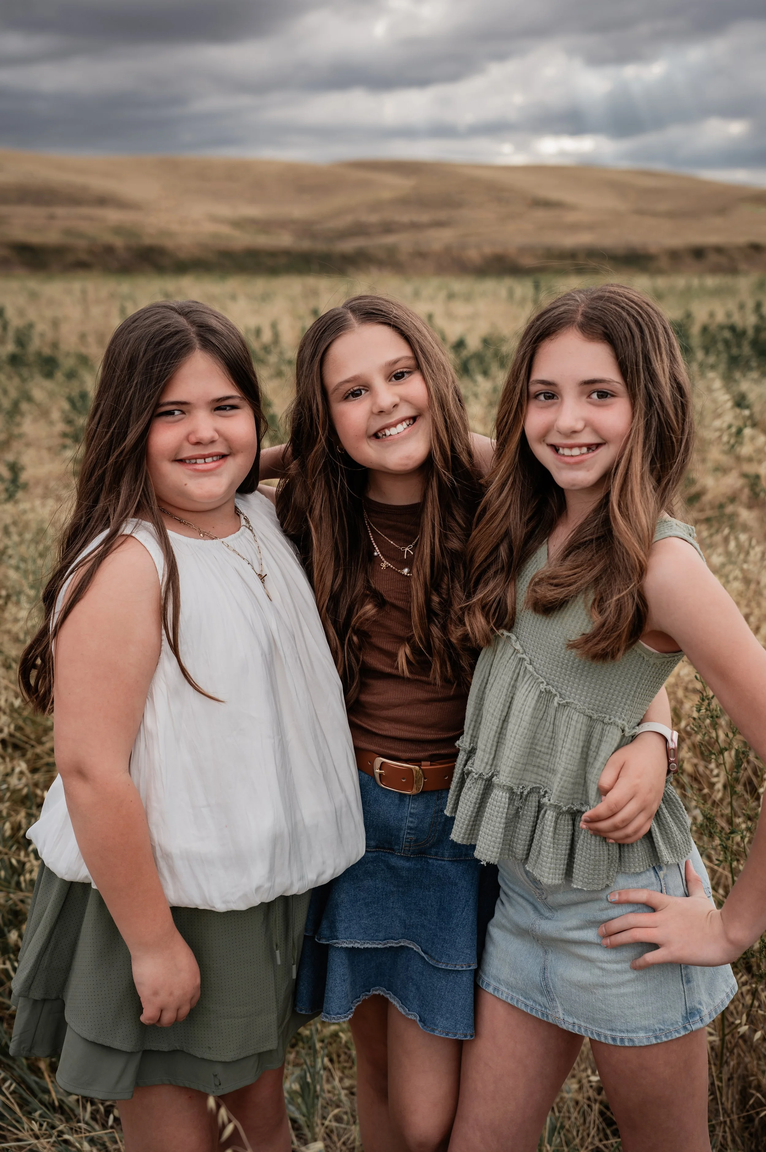 Three female cousins standing in an open field. Photo taken by family photographer, Mikaela Tosta Photography in Patterson, CA.