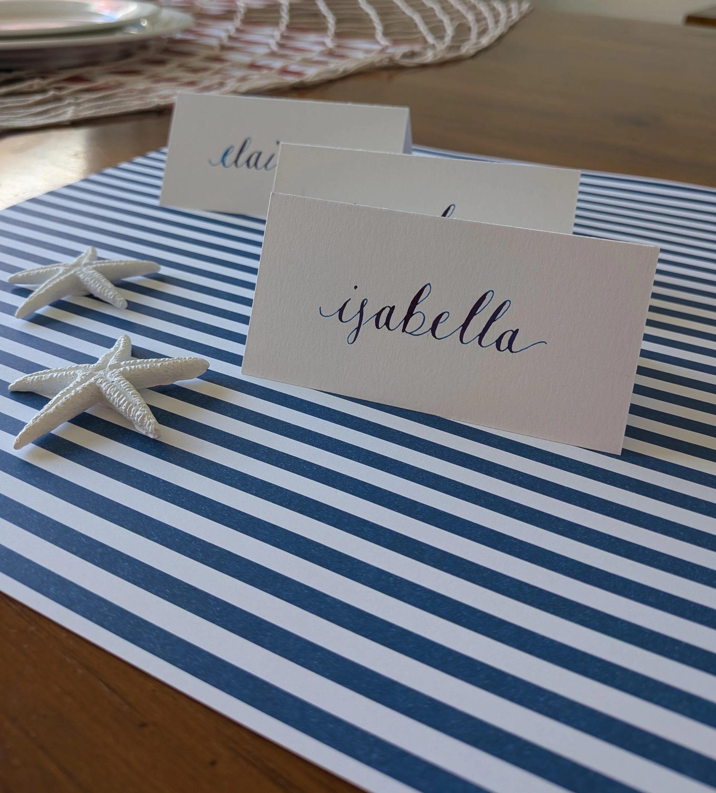 handwritten place cards on blue and white striped table setting with coastal details for Rhode Island wedding