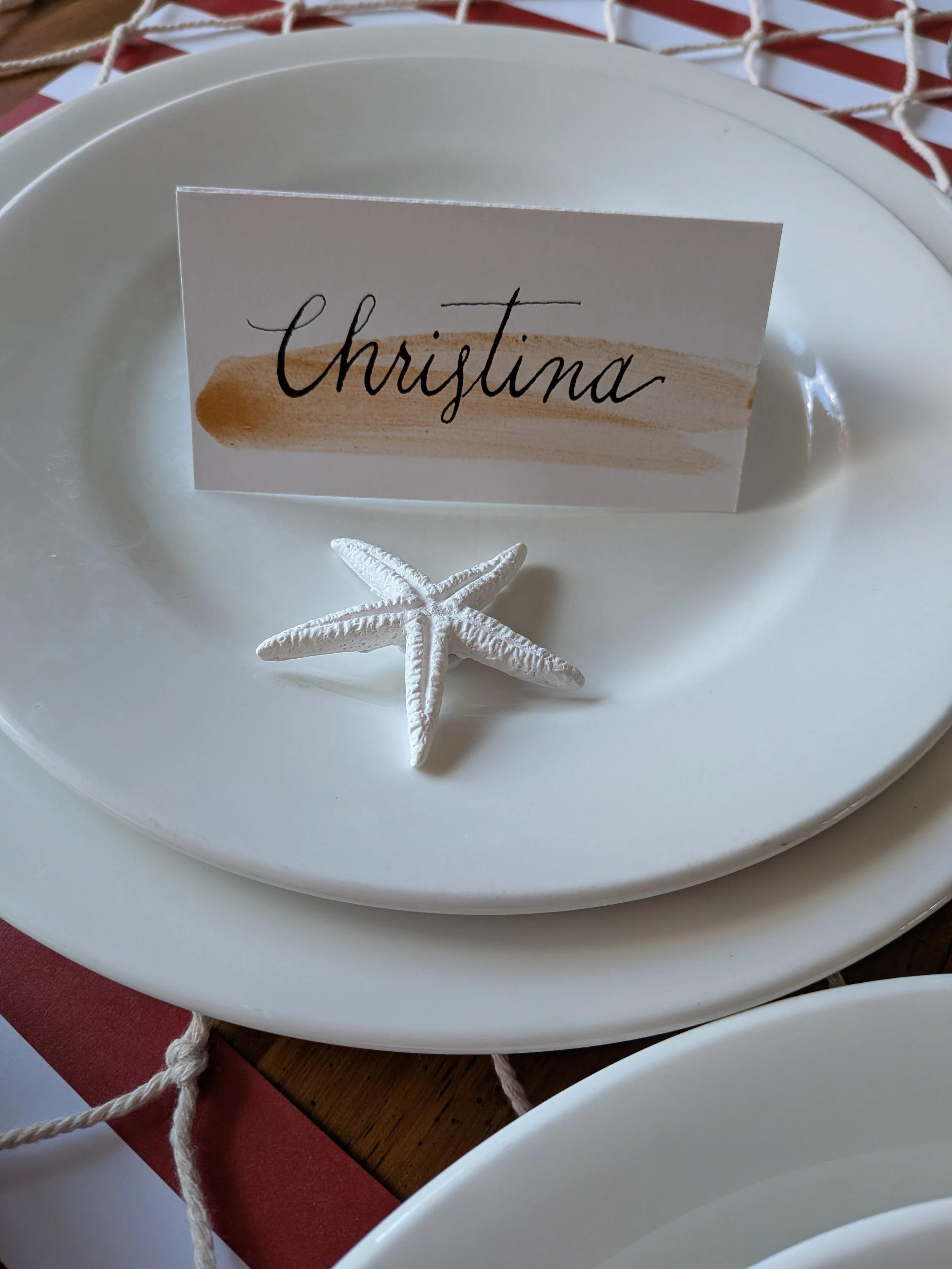 handwritten place card with gold brushstroke detail on plate setting for Rhode Island coastal wedding
