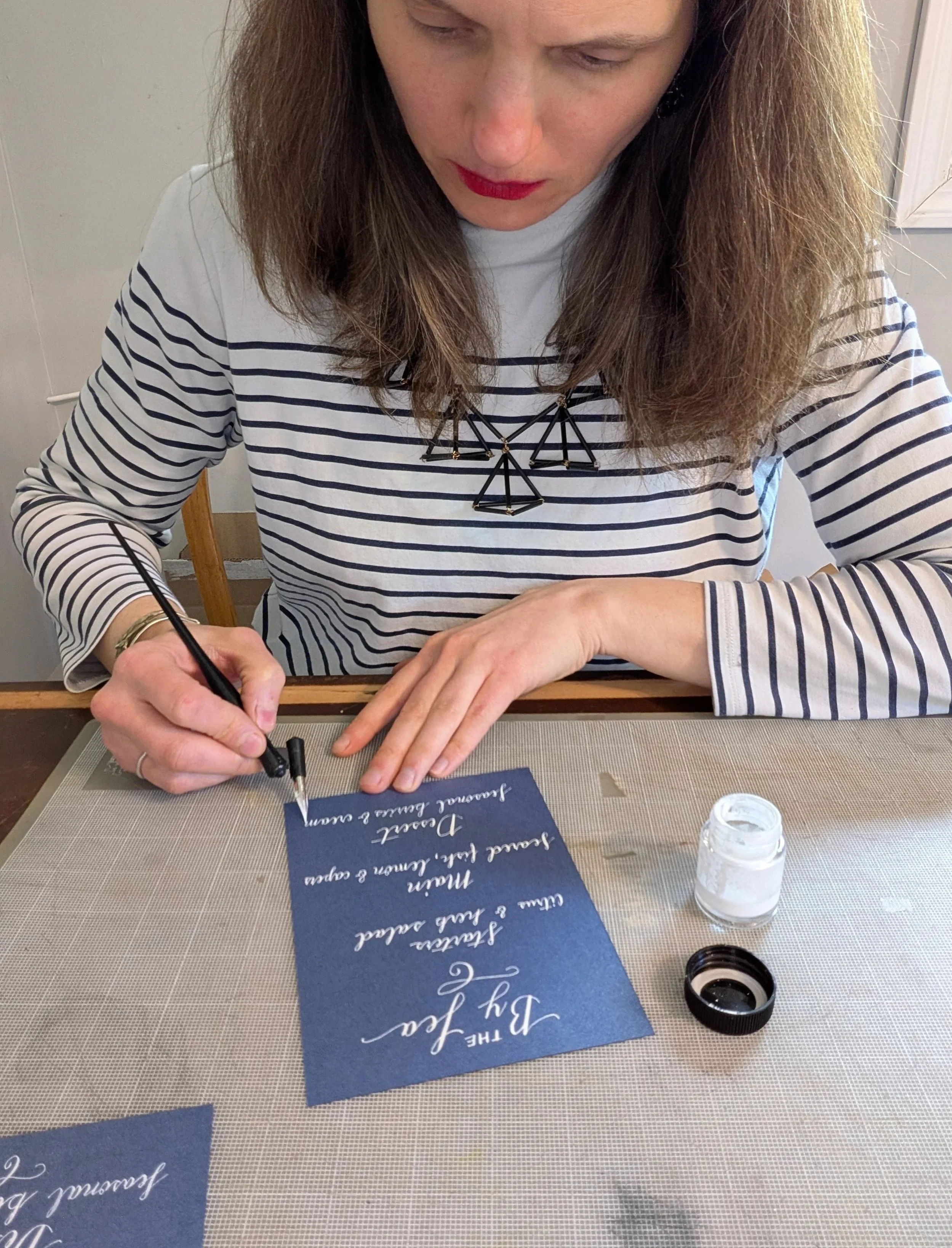 calligrapher hand lettering menu with ink and pen in studio workspace