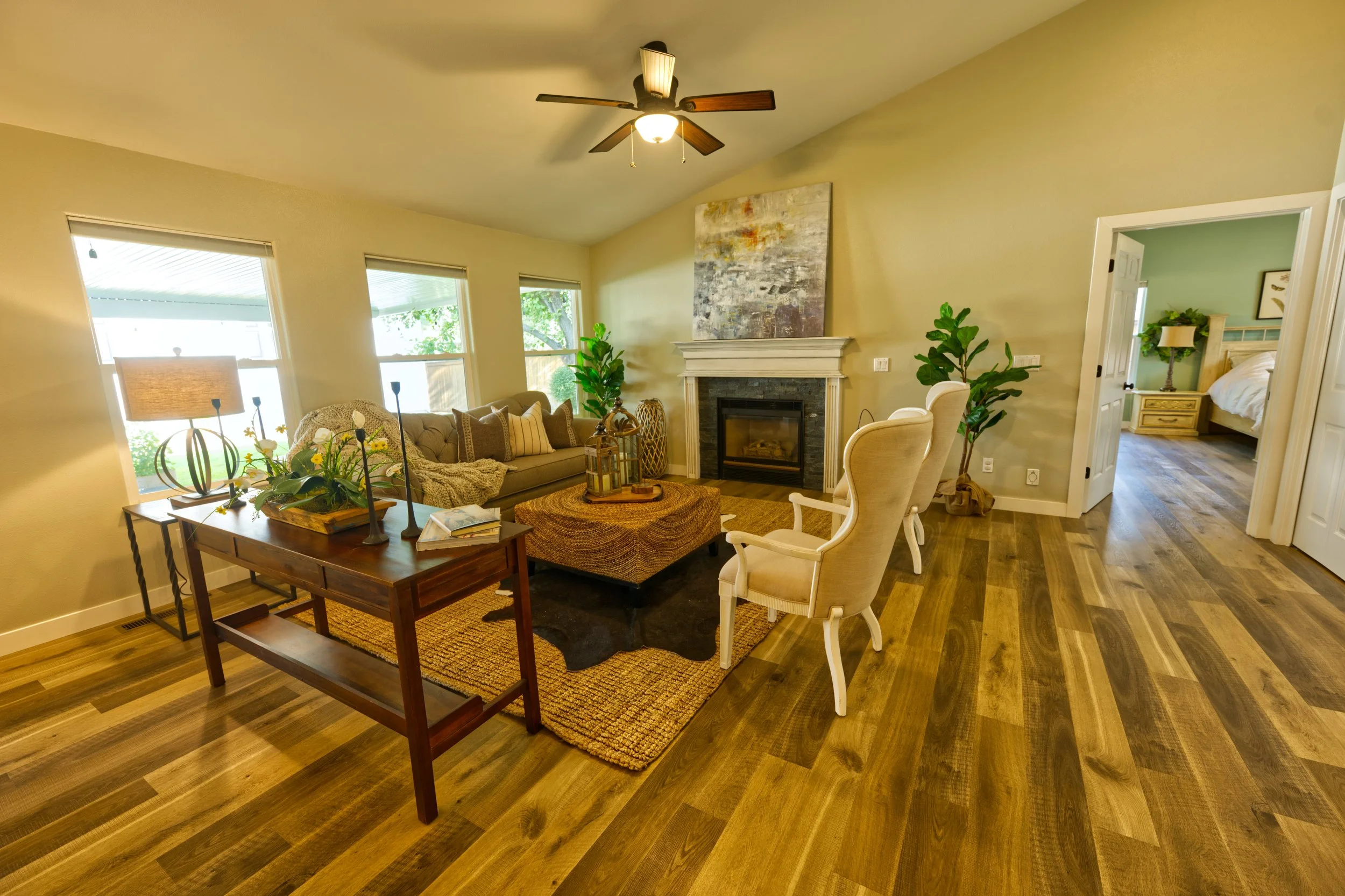 Living room with beige walls, hardwood floors, a fireplace, sofa with throw pillows, and a window with blinds.