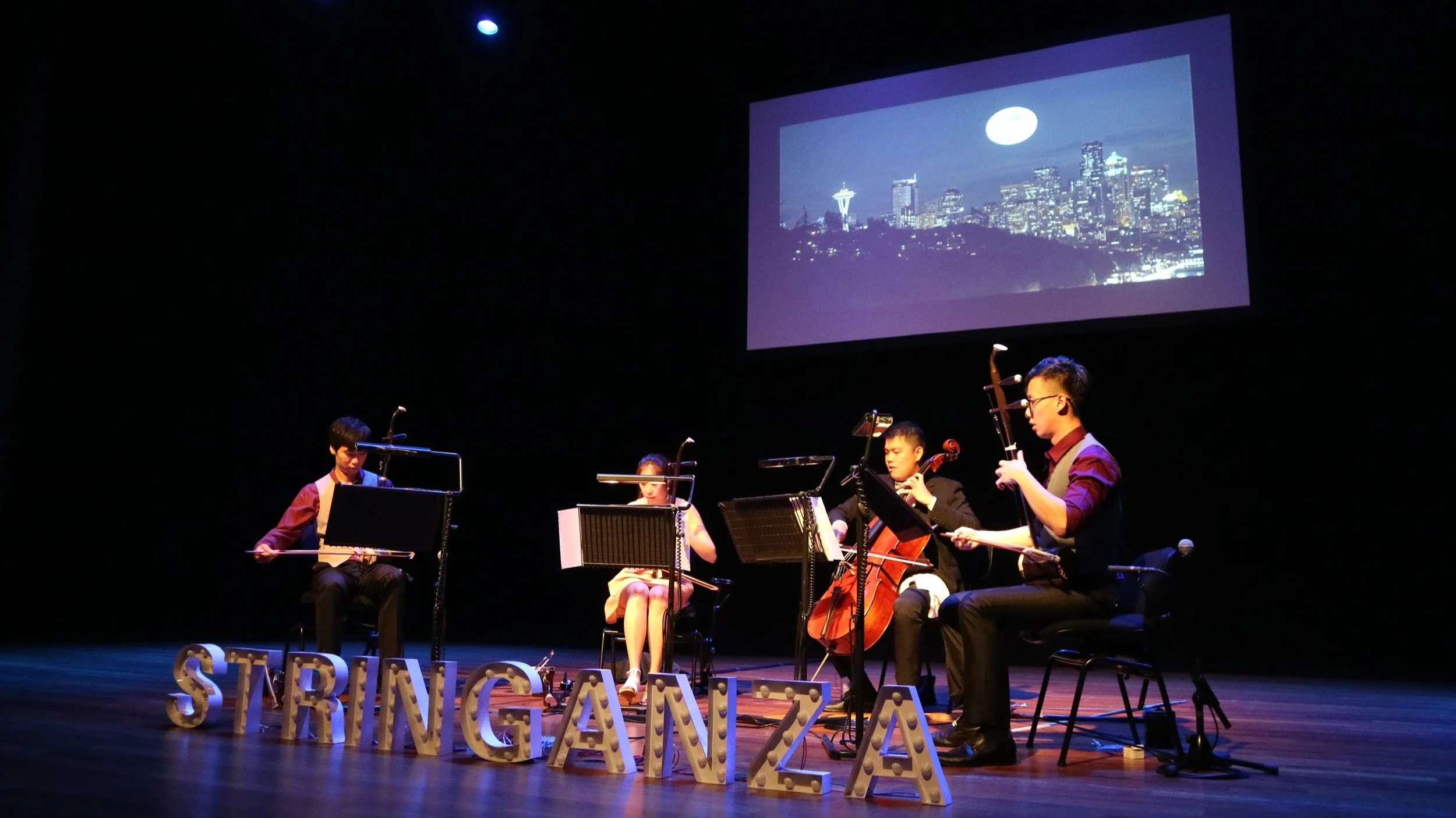 Stringanza Quartet performing at their first ticketed recital SOAR at the Esplanade Recital Studio, under a screen projection showing city under the moonlight