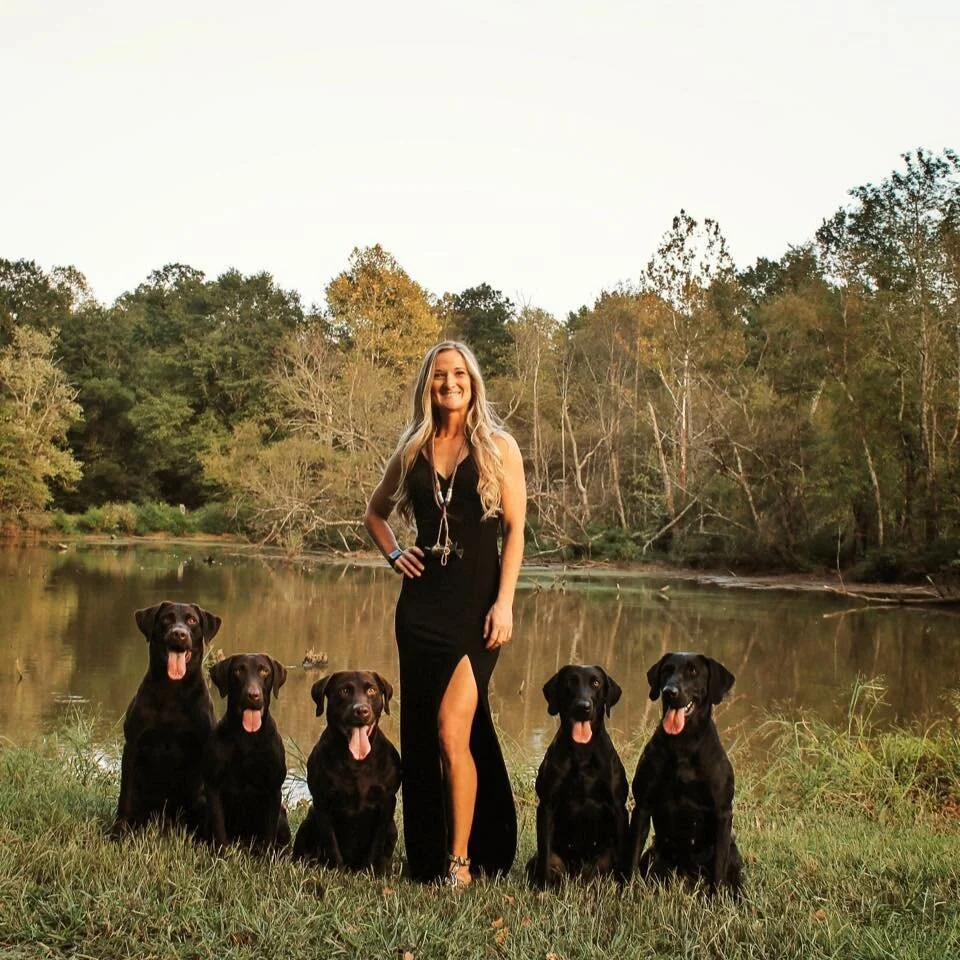 Haley kneeling with arm stretched out teaching dog.