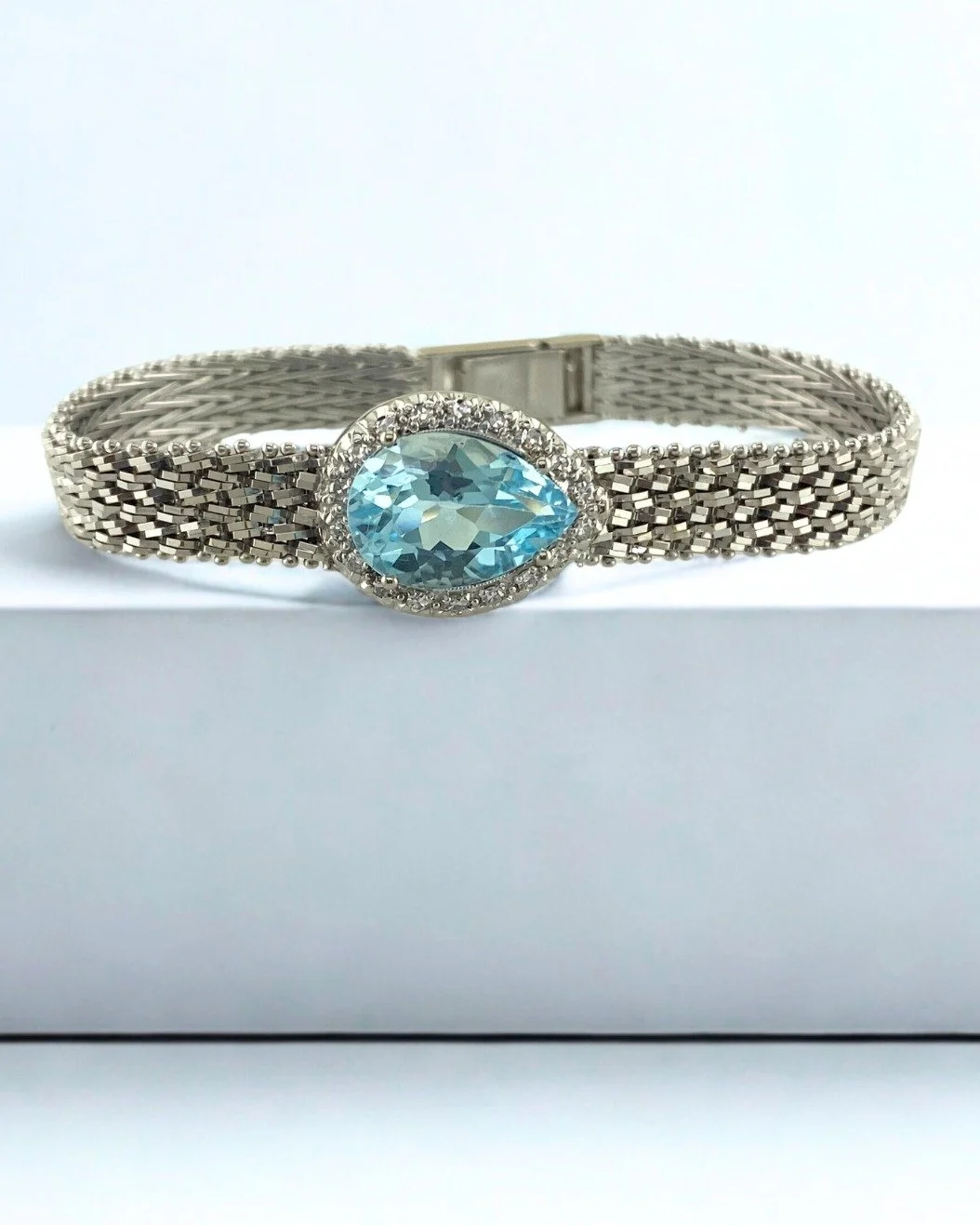 This stunning bracelet comes with a unique backstory! This blue topaz and diamond bracelet was once a vintage watch that was no longer running. We removed the old movement, found the right gemstone to fit the space, and fabricated prongs to set the s