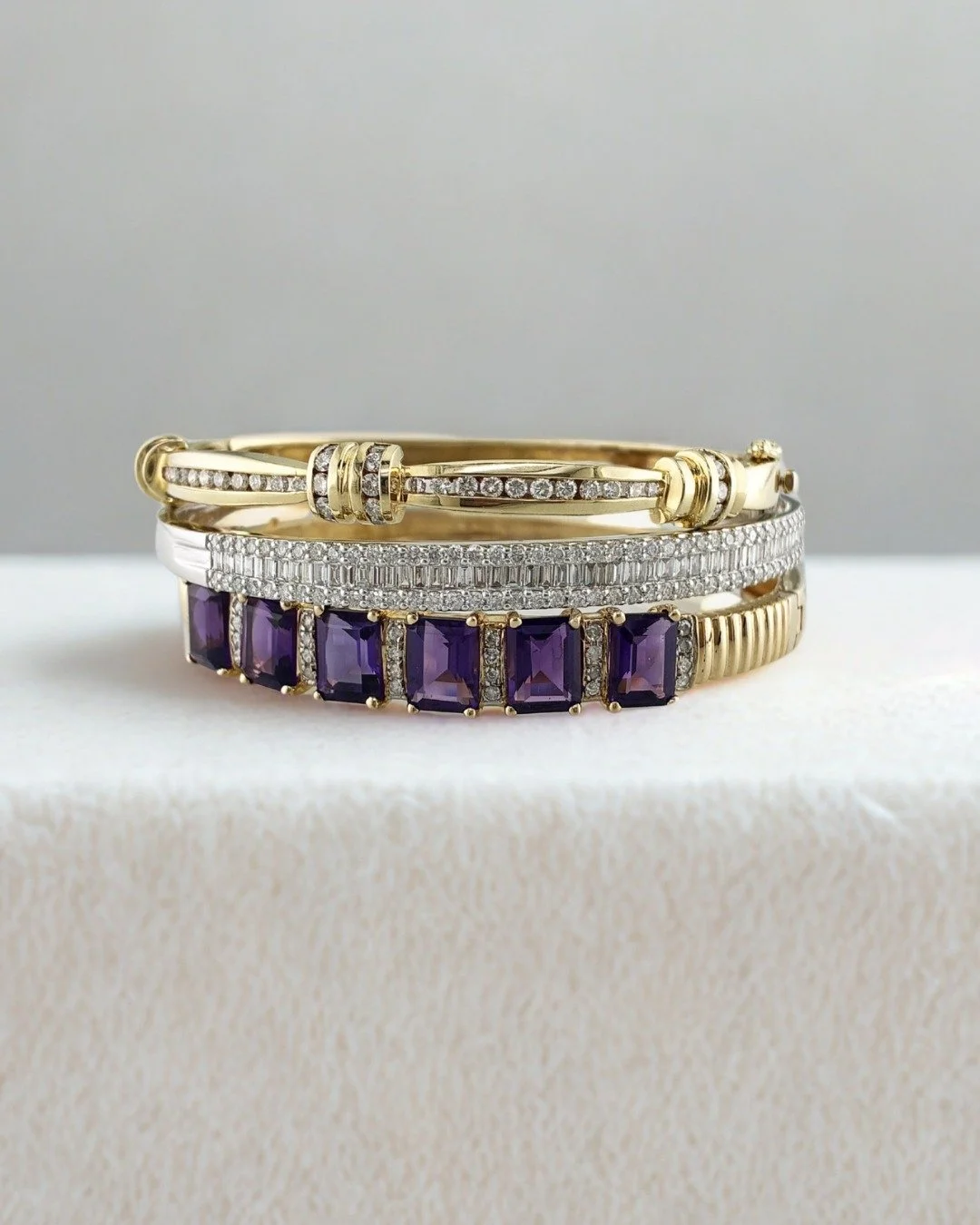 These bangle bracelets all feature diamonds set in 14K gold, but in very different designs. A vintage amethyst and diamond bangle suits a retro style, while this estate diamond bangle in yellow gold has a classic and timeless feel. And for a more mod