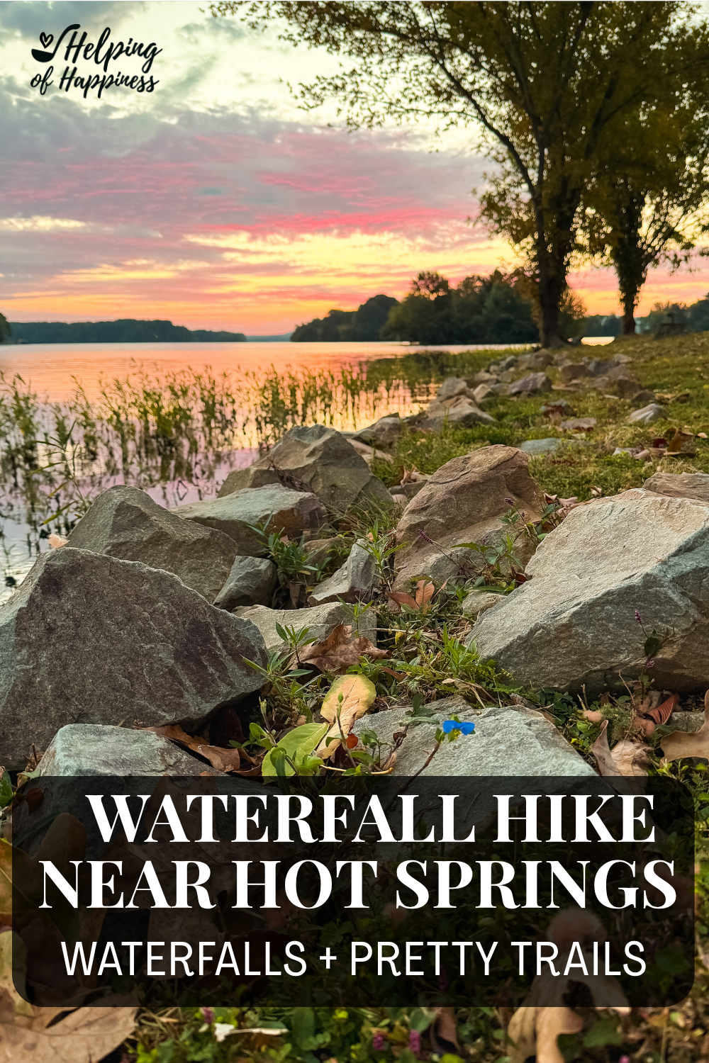 Colorful sunset over Lake Hamilton in Hot Springs, Arkansas, with shoreline rocks, trees, and golden reflections on the water.