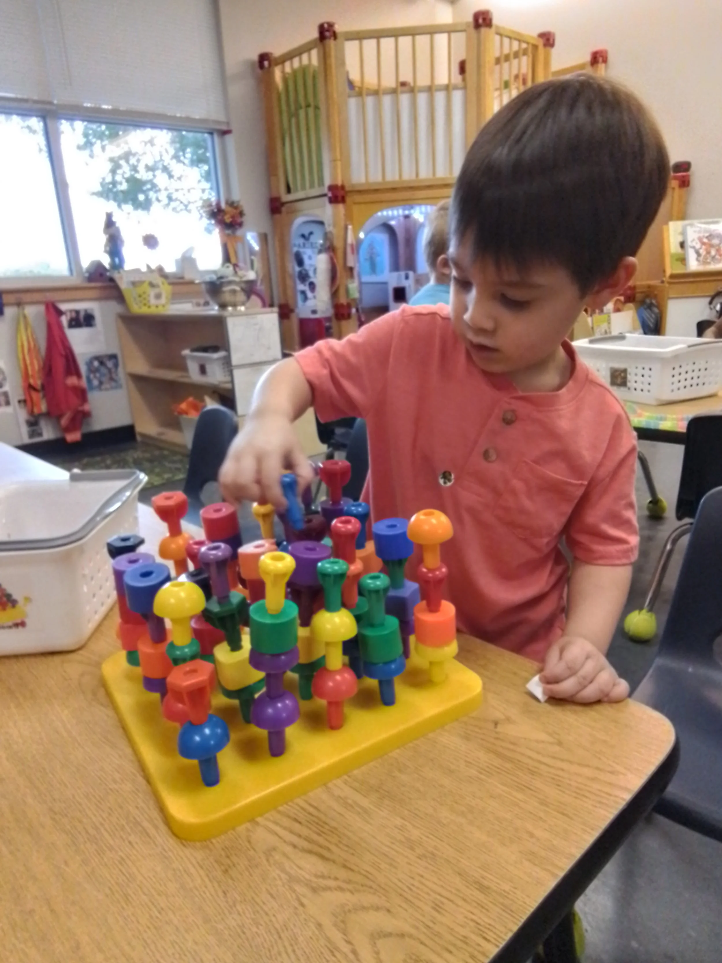 Small child learning through play with a colorful peg counting game