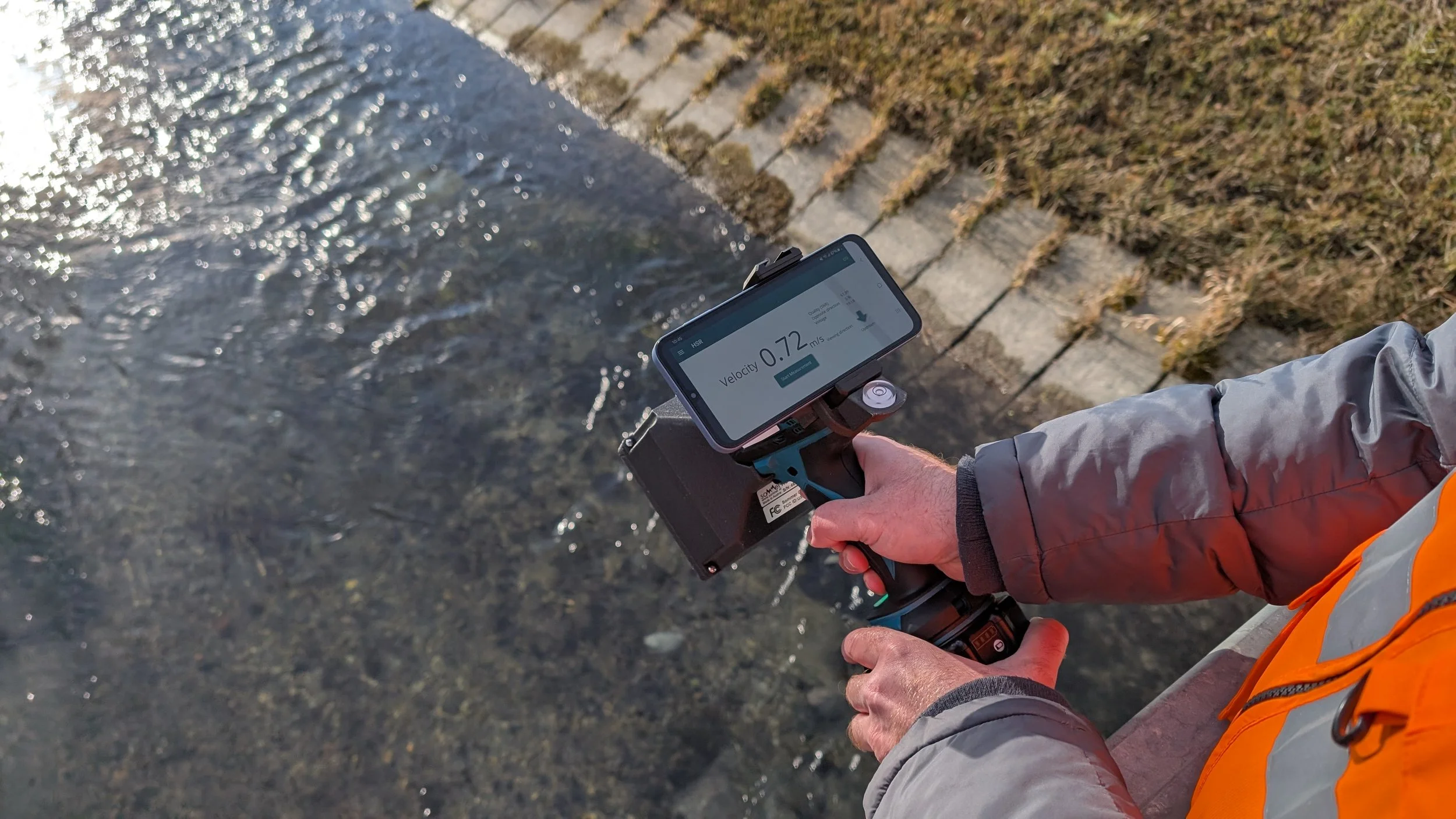 A man taking a water velocity measurement in a channel with an ultrasonic flow meter