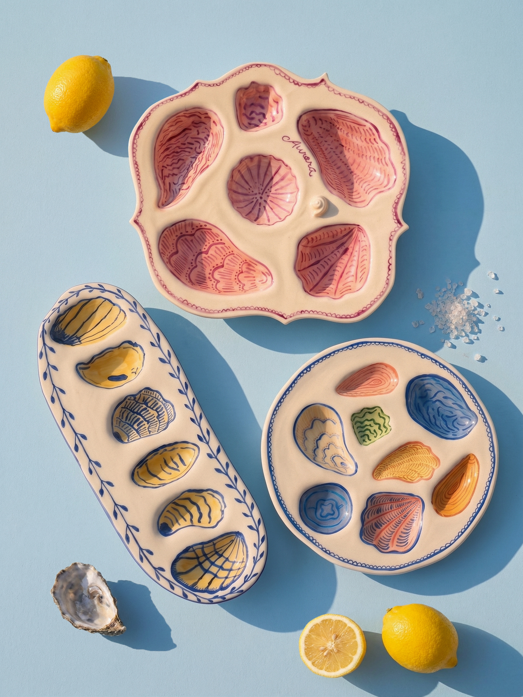 Hand made ceramic Oyster Platters with lemons salt and an oyster shell on a powder blue background