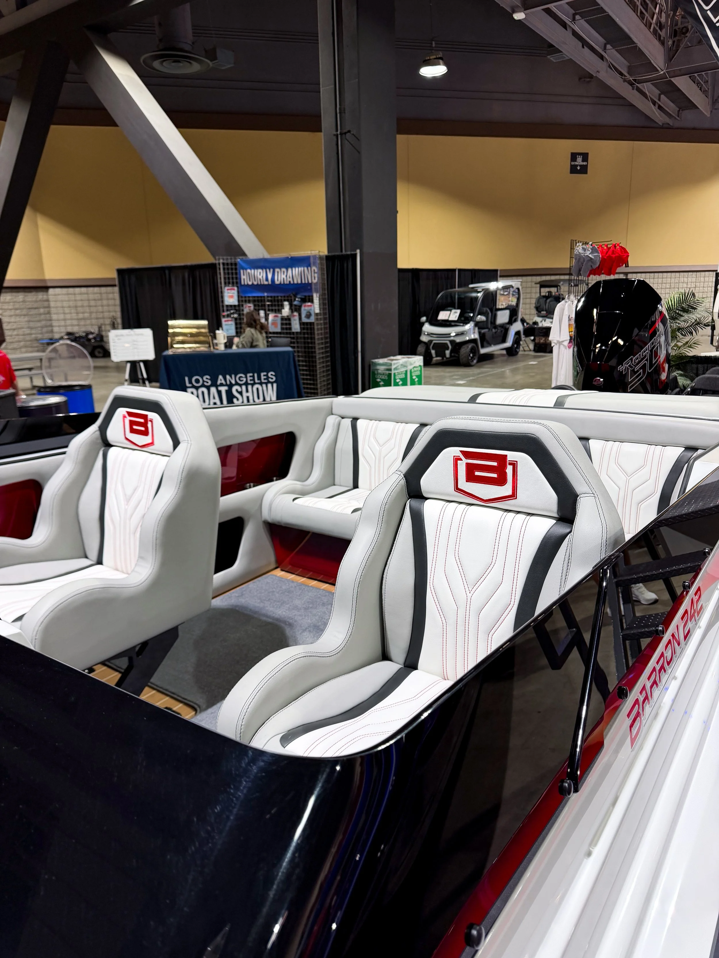 White boat seats with red and black accents at the Los Angeles Boat Show, with a blue tablecloth underneath labeled 'LOS ANGELES BOAT SHOW'.