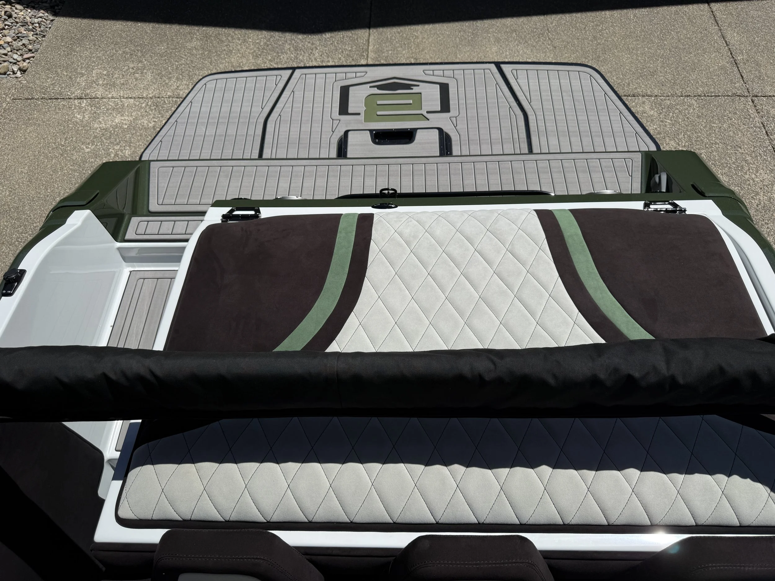 Overhead view of a pickup truck bed with a black, green, and white quilted blanket and a green and black plaid blanket, parked on a concrete driveway.