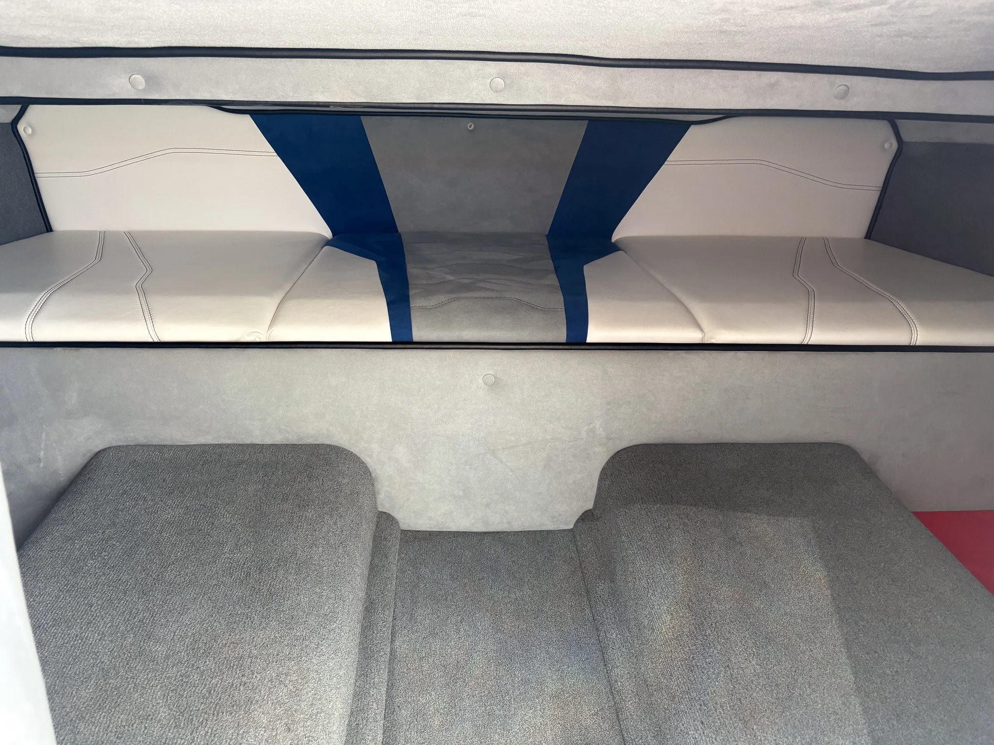 Interior of a small transport vehicle or shuttle with cushioned seats and gray fabric walls.