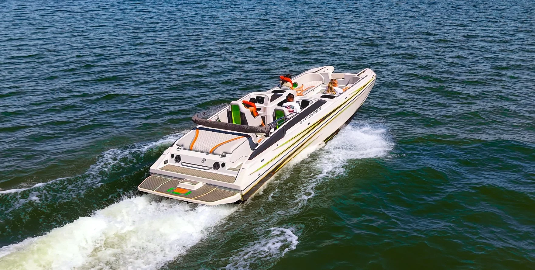A white motorboat speeding across the water with four passengers on board, surrounded by choppy greenish-blue water.