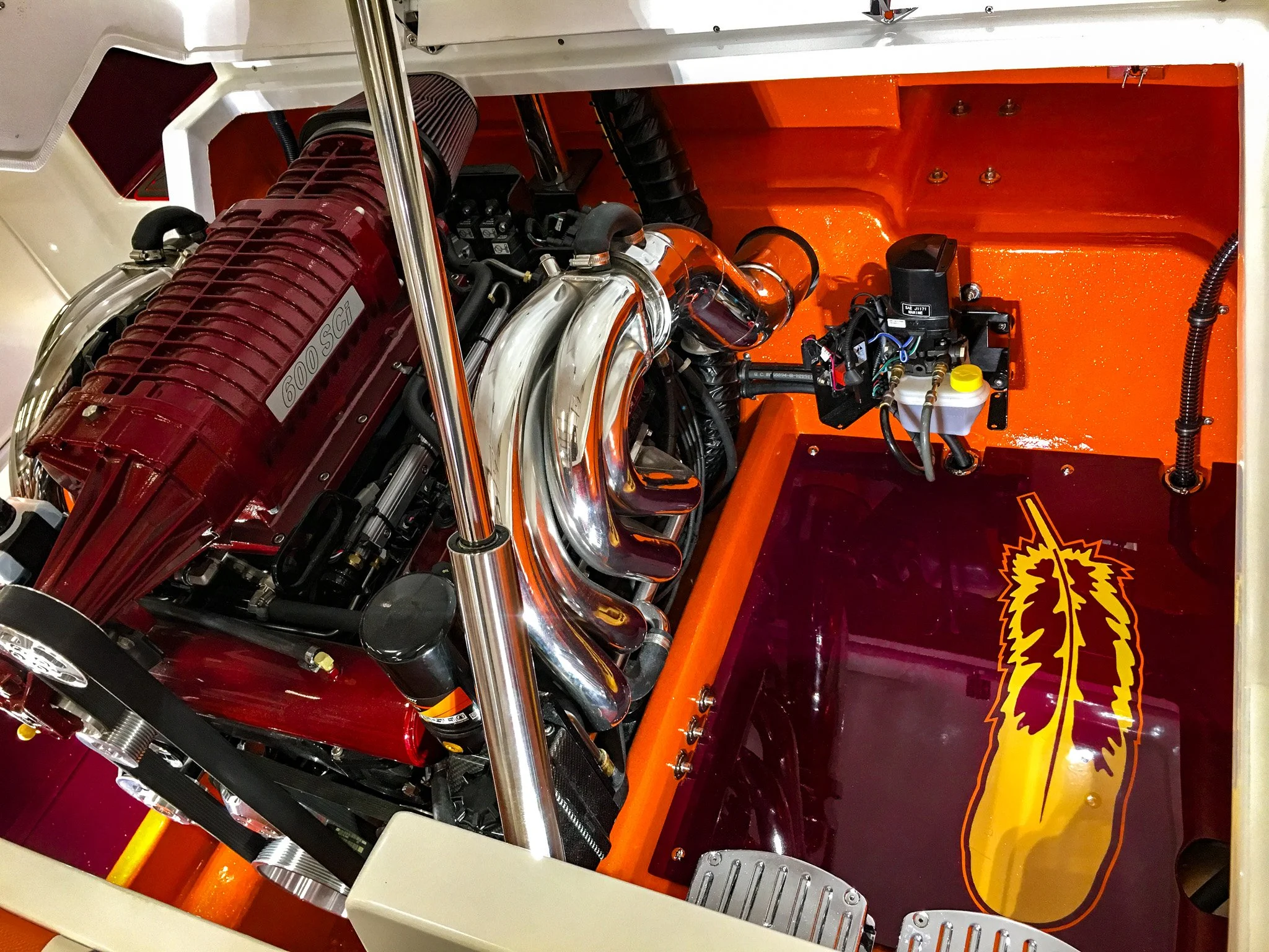 Close-up of an engine inside a vehicle with orange and cream-colored interior, featuring chrome components and a lion logo decal.