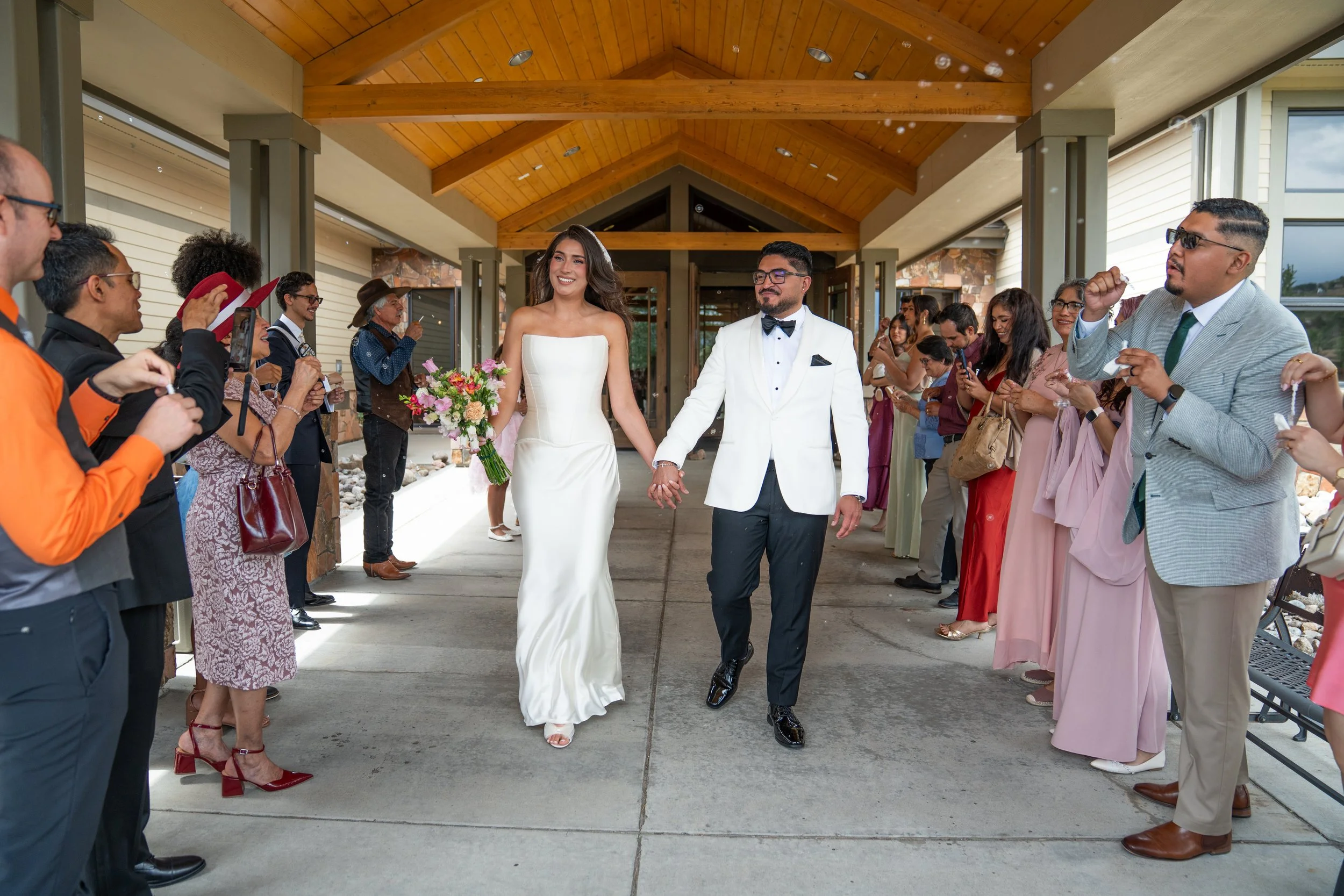 A bride and groom holding hands walking through a line of guests at their wedding.